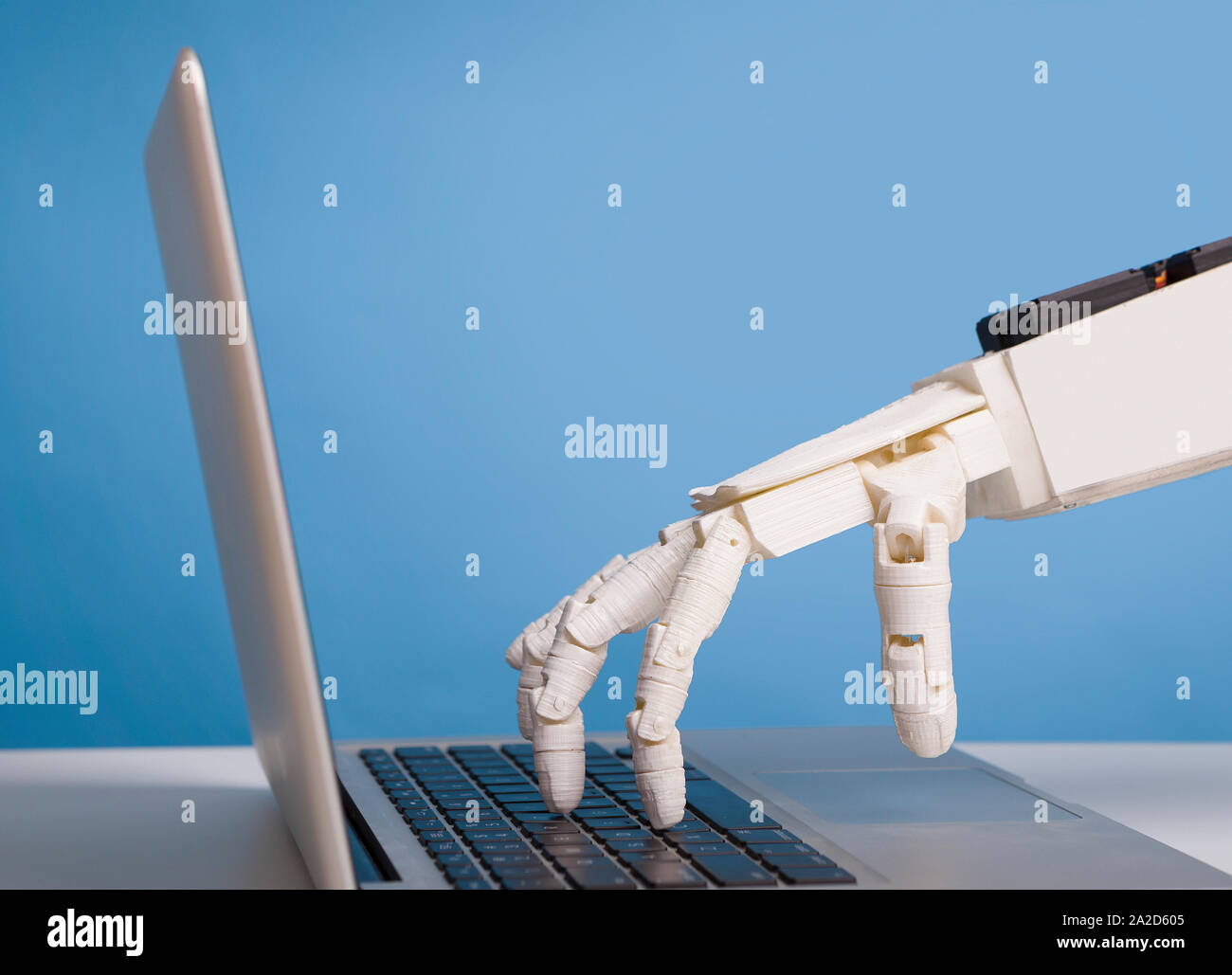 Robotic hand typing on laptop keyboard, free space Stock Photo