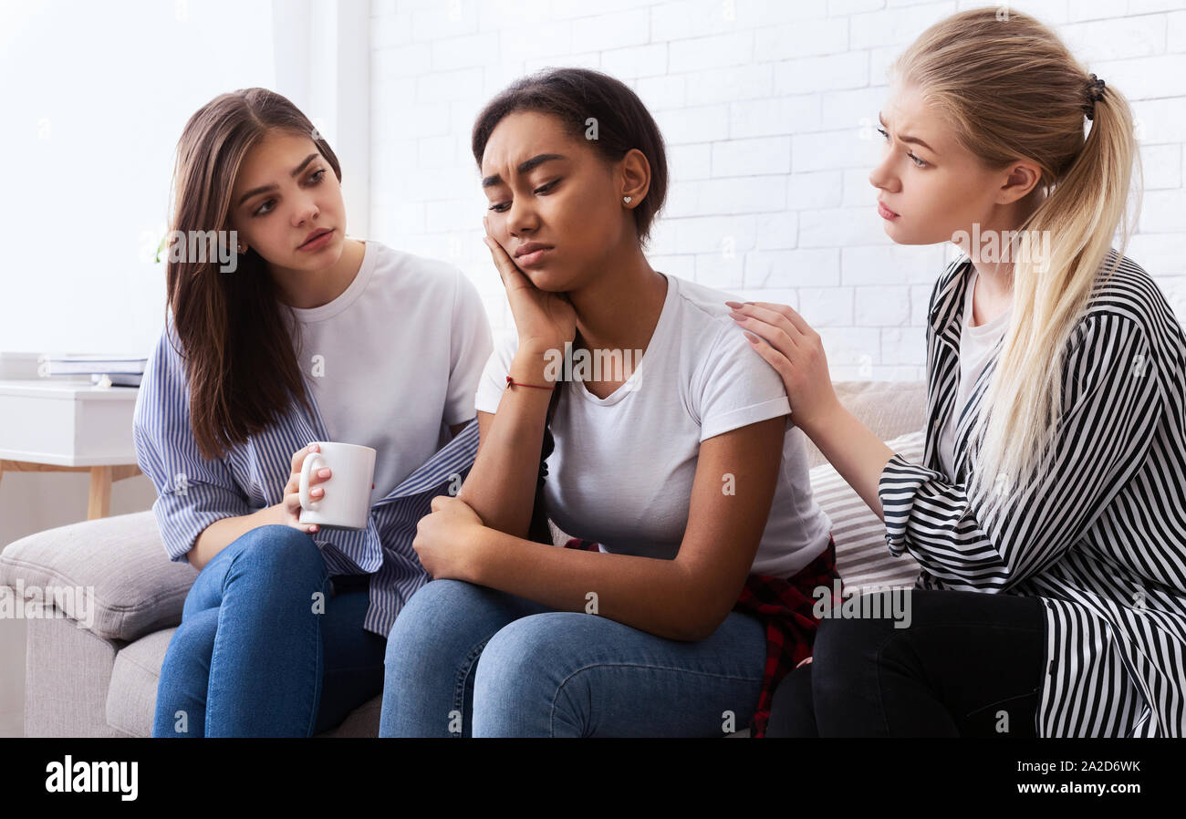 Teen girls comforting their upset friend at home Stock Photo