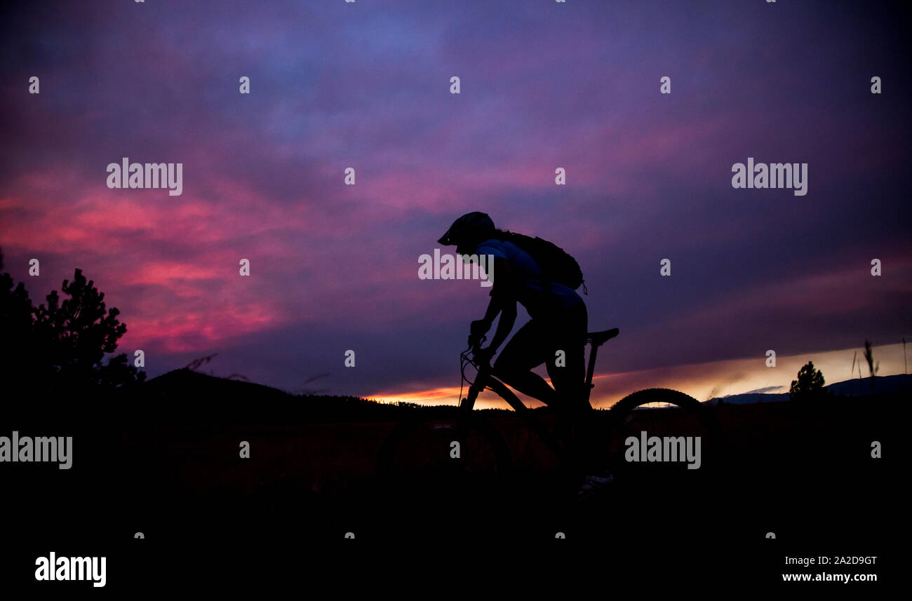 A woman mountain biker rides at sunset near Missoula, Montana. Stock Photo