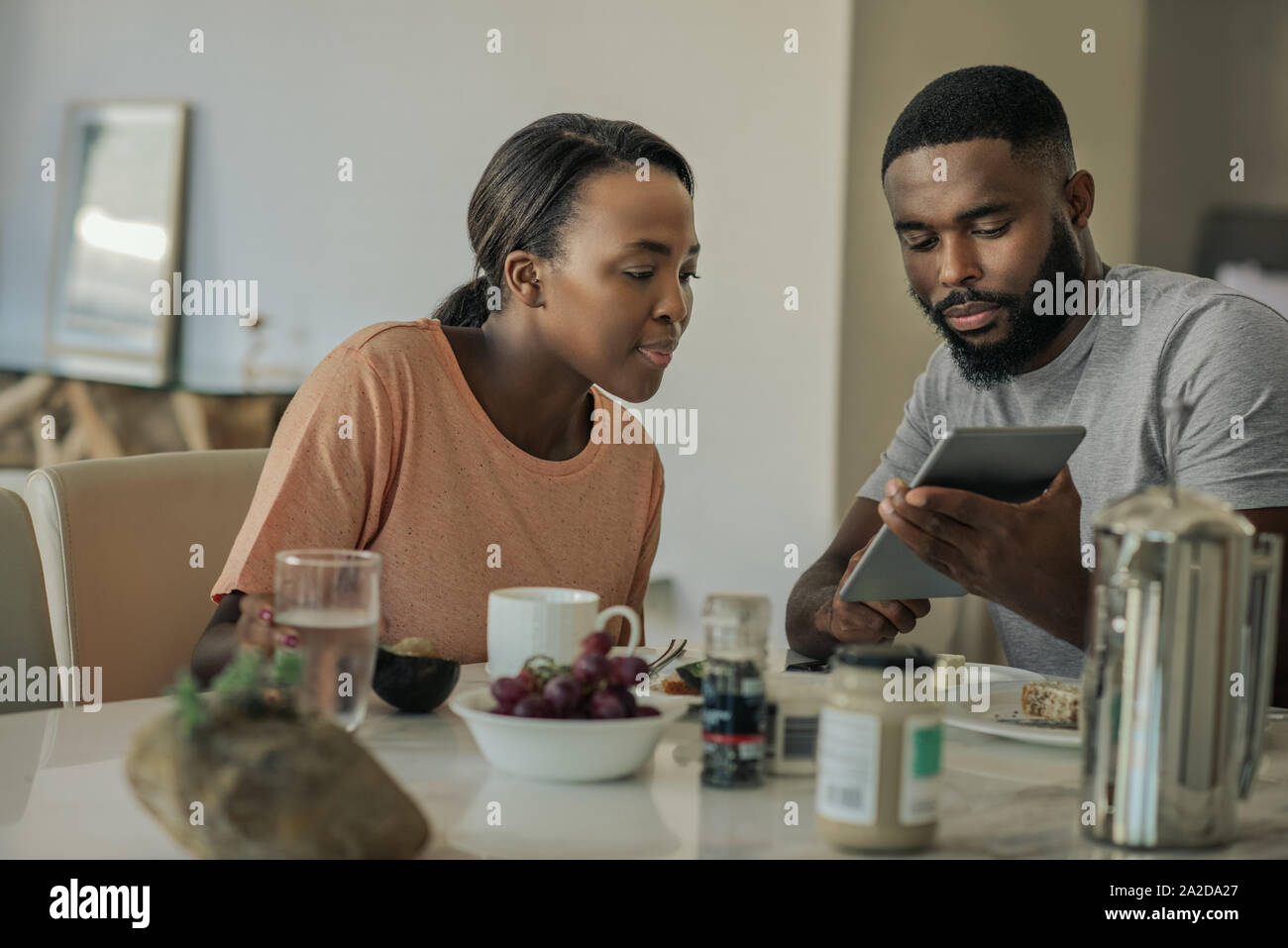 Smiling young African American couple using a tablet over breakfast Stock Photo