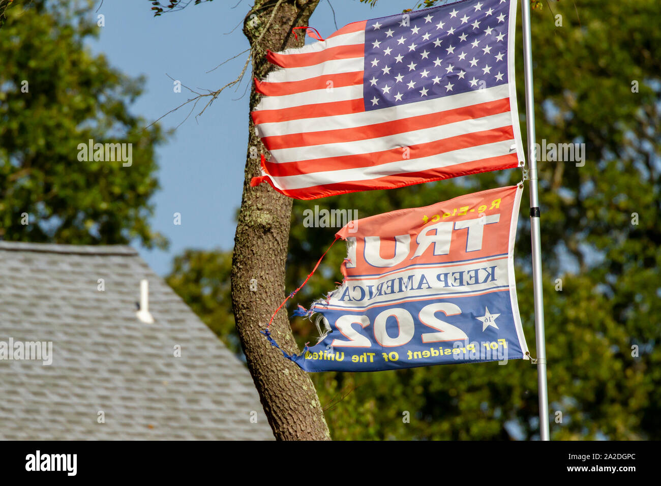 Cape May, New Jersey - September 28, 2019 :  Tattered and torn Trump re-election flag on flagpole with shredded American flag. Stock Photo