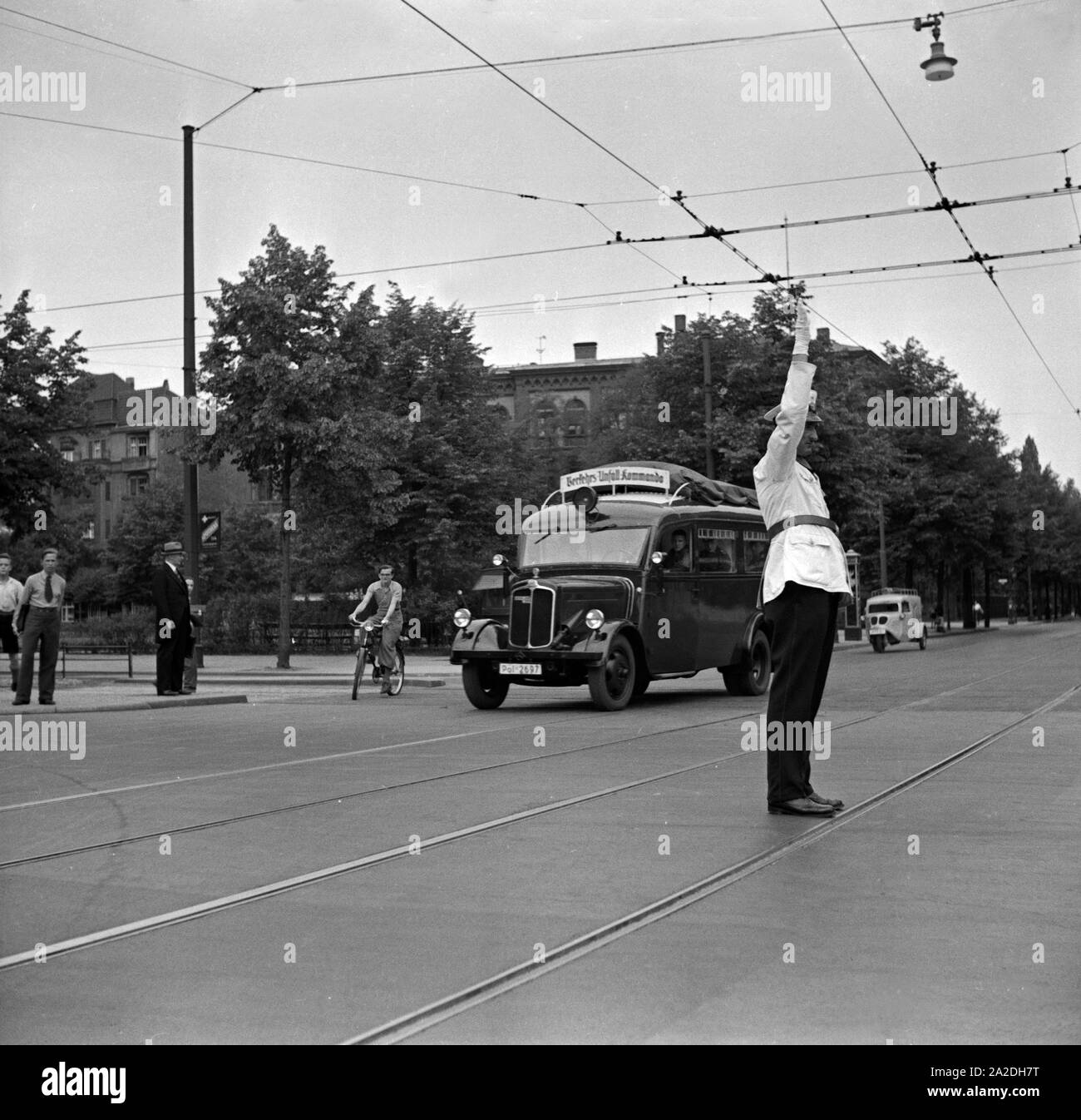 Der Querverkehr wird angehalten, damit der Einsatzwagen des Verkehrsunfallkommandos freie Fahrt hat, Deutschland 1930er Jahre. Traffic has to stop because for free street for the police car of the Verkehrsunfallkommando, Germany 1930s. Stock Photo