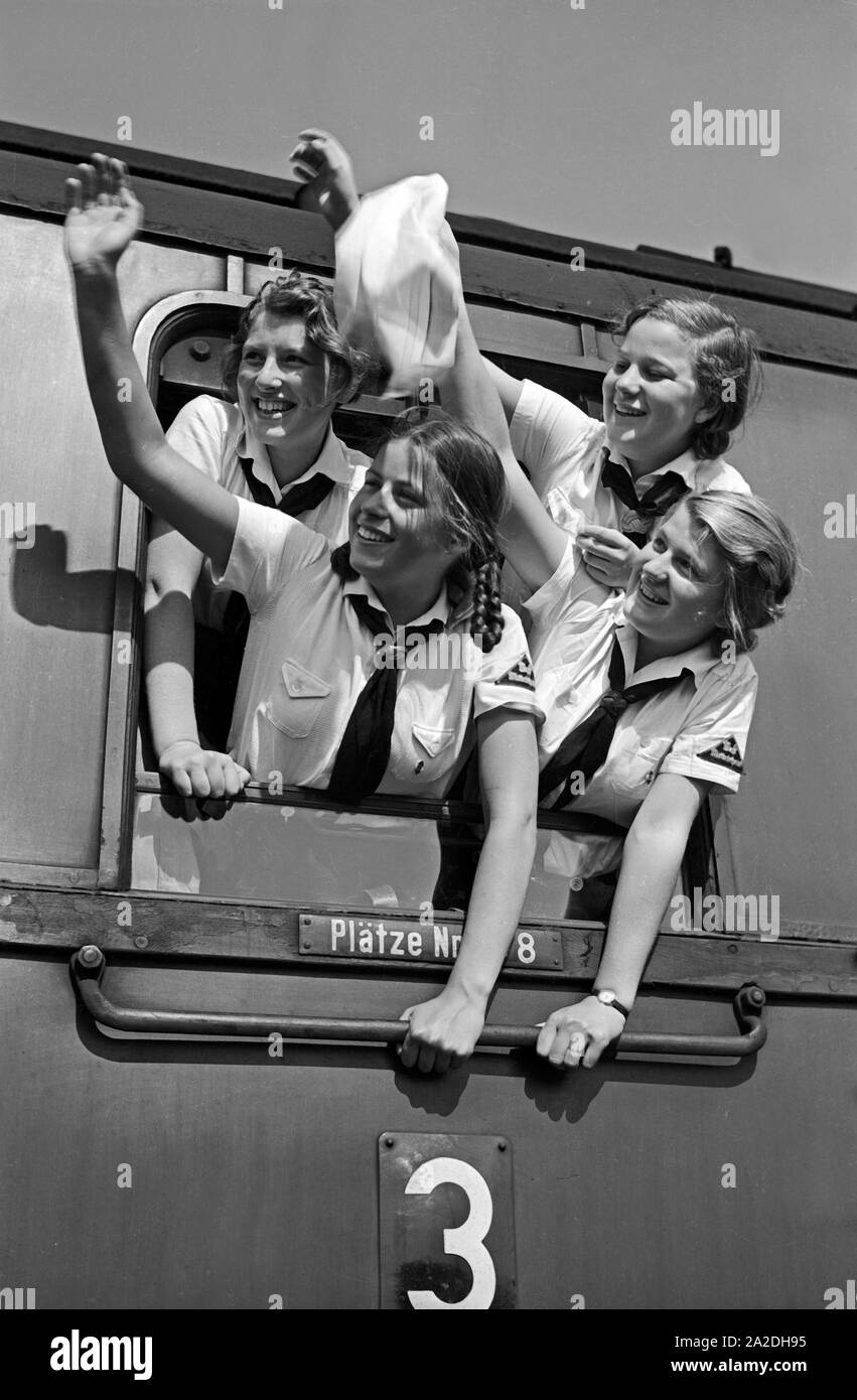 Vier fröhliche BdM Mädel winken zum Abschied aus dem Zugfenster, Deutschland 1930er Jahre. Four happy BdM girls waving out of the window of a train, Germany 1930s. Stock Photo