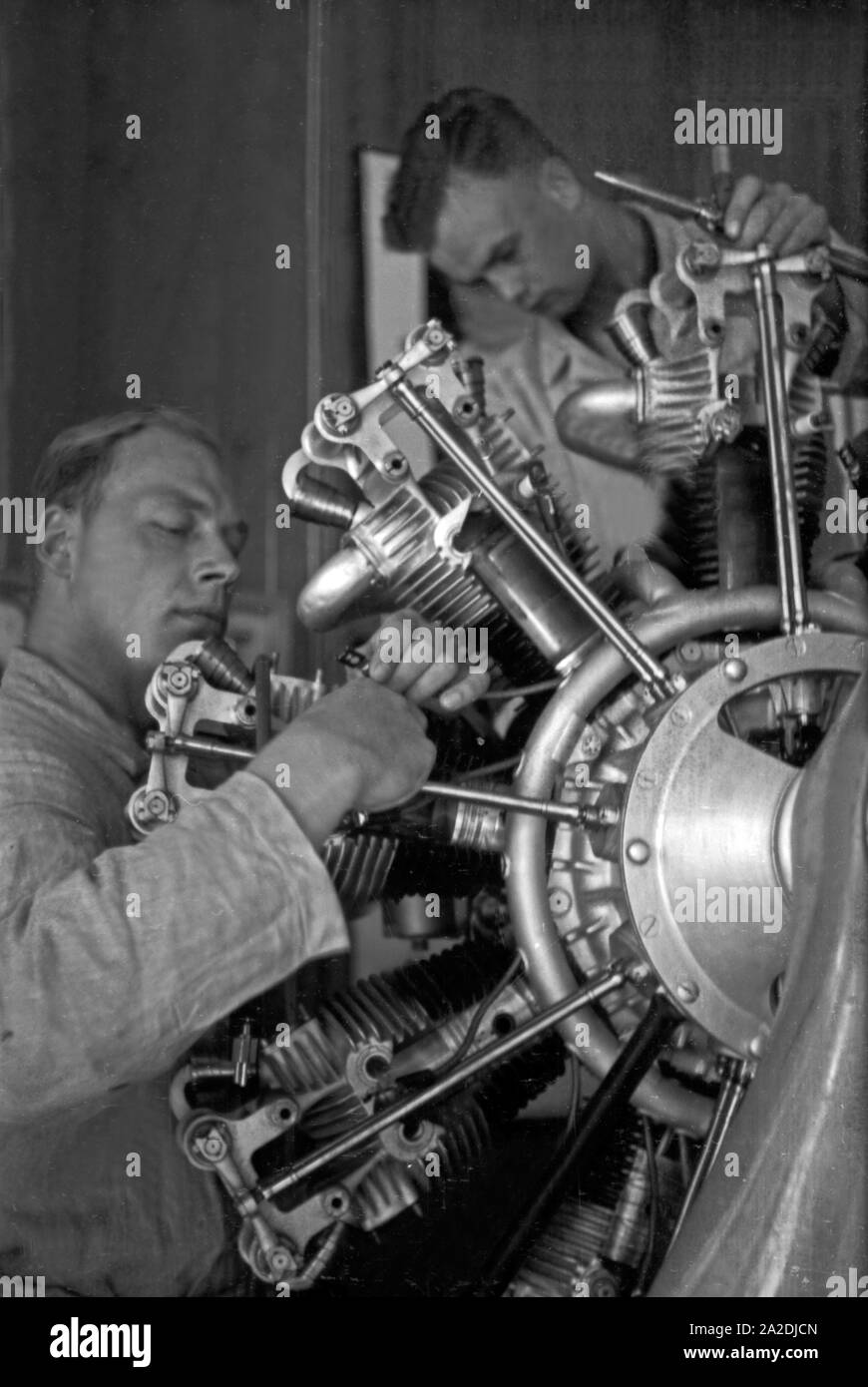 Zwei Mechaniker schrauben an einem Flugzeugmotor bei der Flieger Ausbildungsstelle Schönwalde, Deutschland, 1930er Jahre. Two mechanics srewing an airplane engine, Germany 1930s. Stock Photo