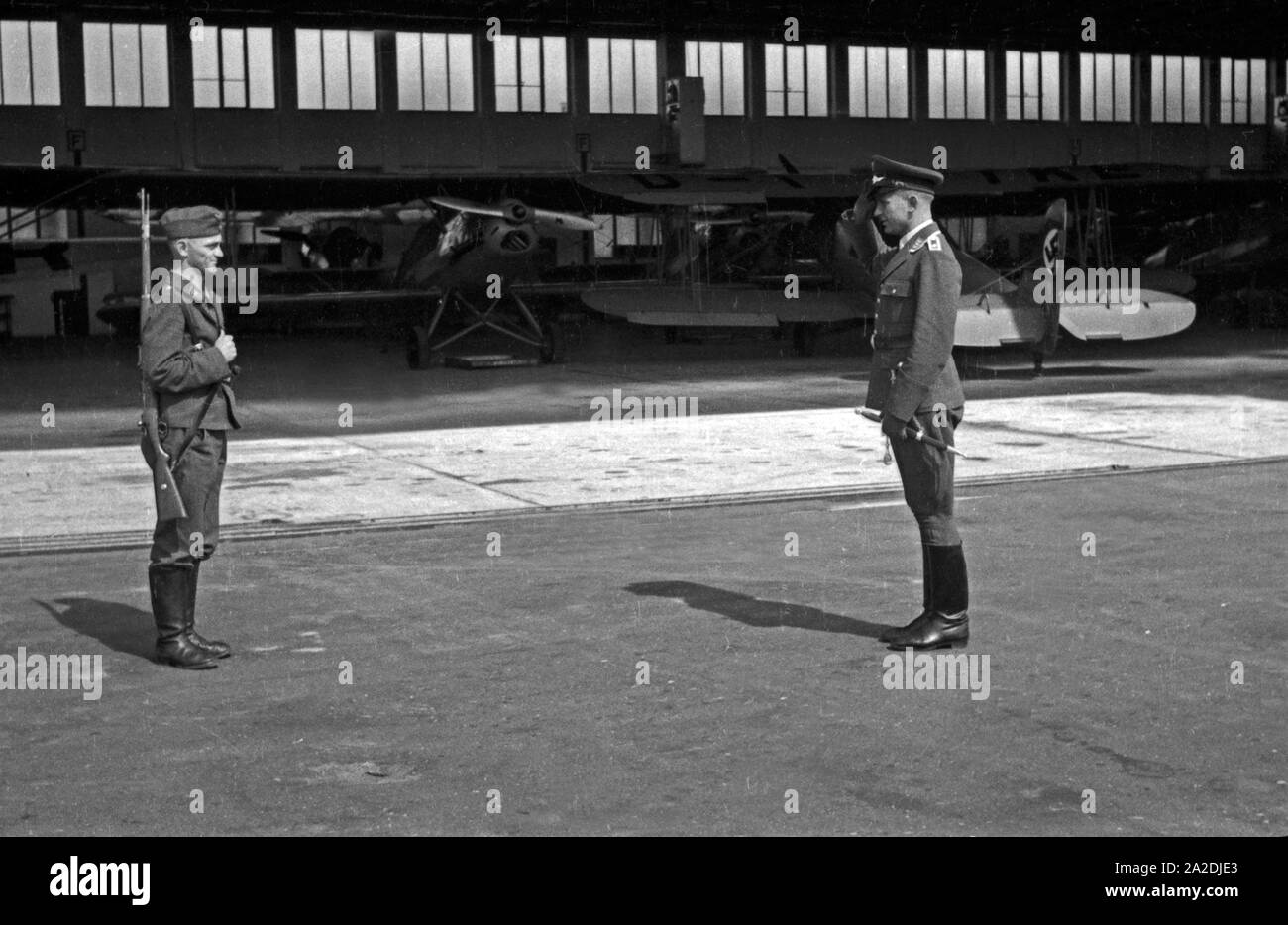 Wachsoldat bei der Meldung an den Offizier am Hangar der Flieger Ausbildungsstelle Schönwalde, Deutschland 1930er Jahre. Soldier on sentinel and officer at a hangar, Germany 1930s. Stock Photo
