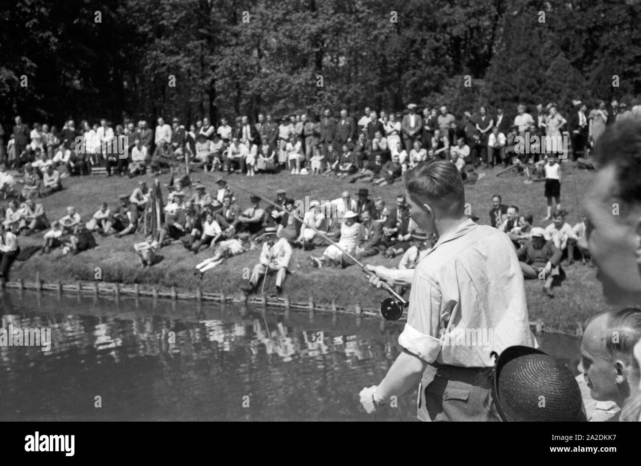 Junger erfahrener Profi Angler angelt an einem Steg, Deutschland, 1930er Jahre. Young professional fisherman fishing on the shore of a lake, Germany 1930s. Stock Photo