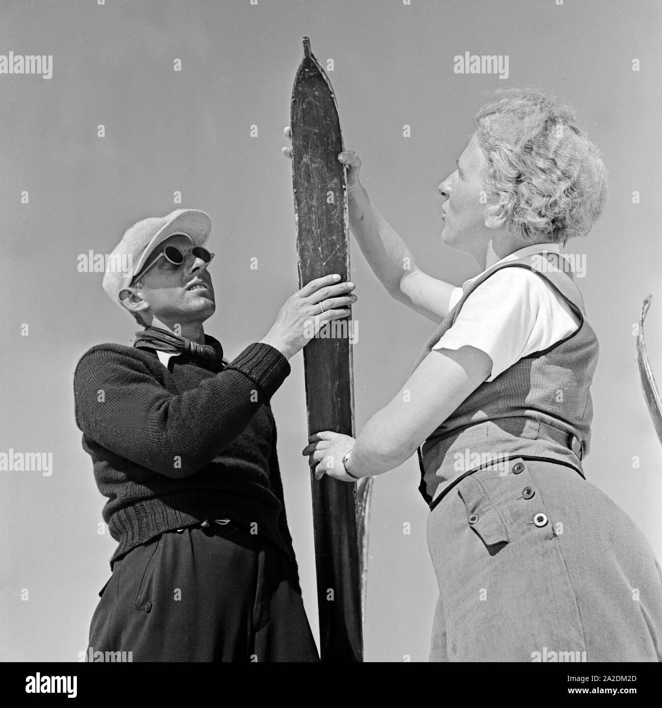 Zwei Skifahrer fachsimpeln über ihre Skier, Deutschland 1930er Jahre. Two ski tourists talking shop about their skis, Germany 1930s. Stock Photo