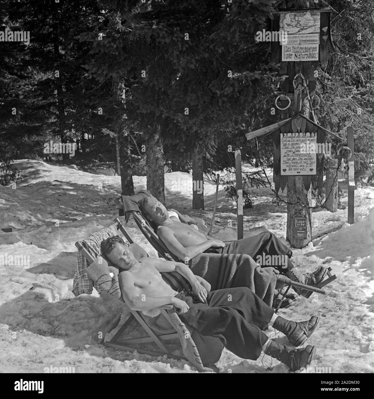 Skiläufer machen eine Pause und nehmen ein Sonnenbad, Deutschland 1930er Jahre. Ski tourists tanning while having a break, Germany 1930s. Stock Photo