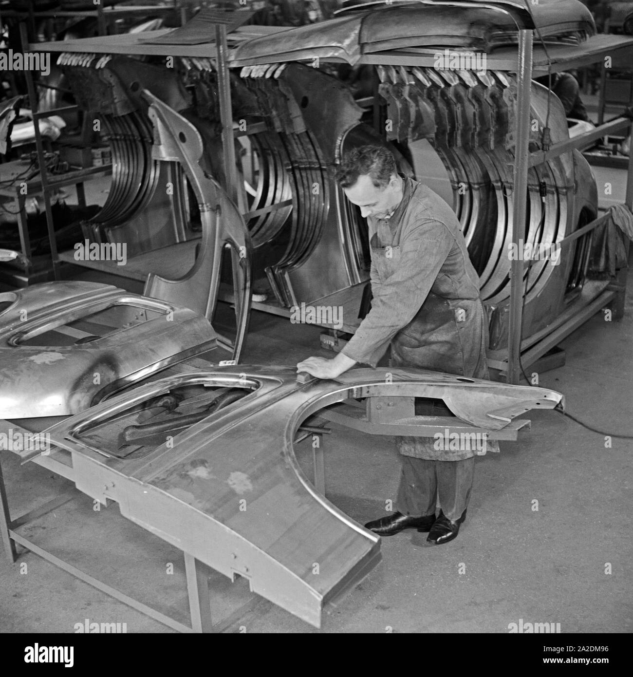 Ein Arbeiter der Ford Werke in Köln Niehl mit Karosserie Teilen, Deutschland 1930er Jahre. A worker with chassis parts at the Ford factory at Cologne, Germany 1930s. Stock Photo