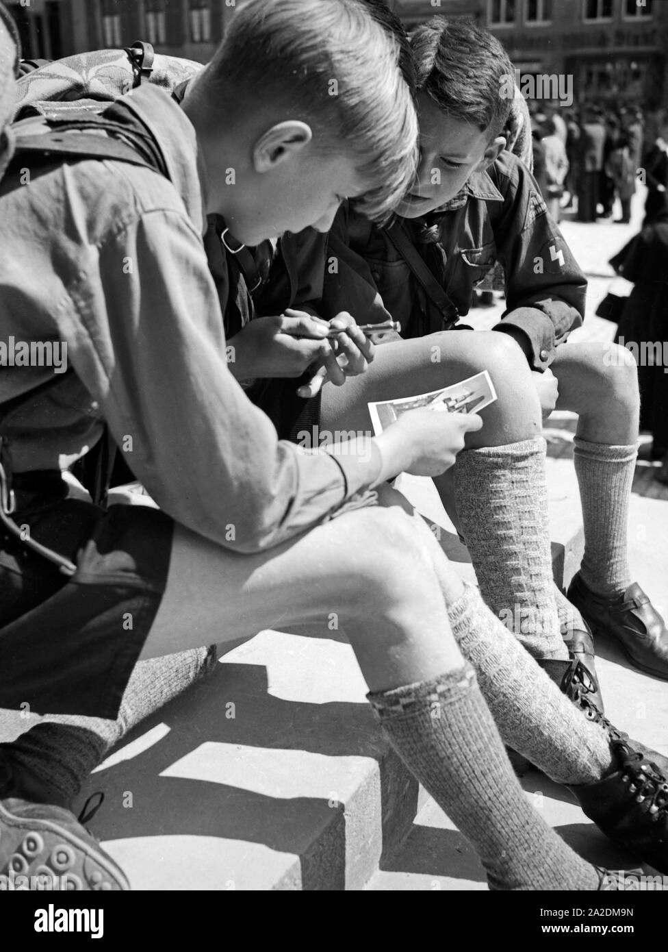 Drei Hitlerjungen schreiben eine Postkarte von einer Wanderung, Deutschland 1930er Jahre. Three Hitler youths writing a postcard from a wandering trip, Germany 1930s. Stock Photo