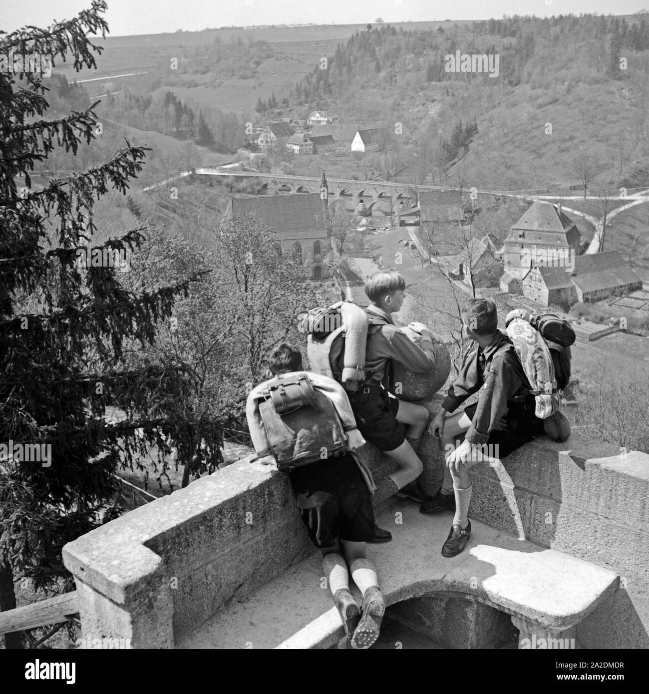 Drei Hitlerjungen schauen auf ein Dorf, Deutschland 1930er Jahre. Three Hitler youths watching a village from a  watchout, Germany 1930s. Stock Photo