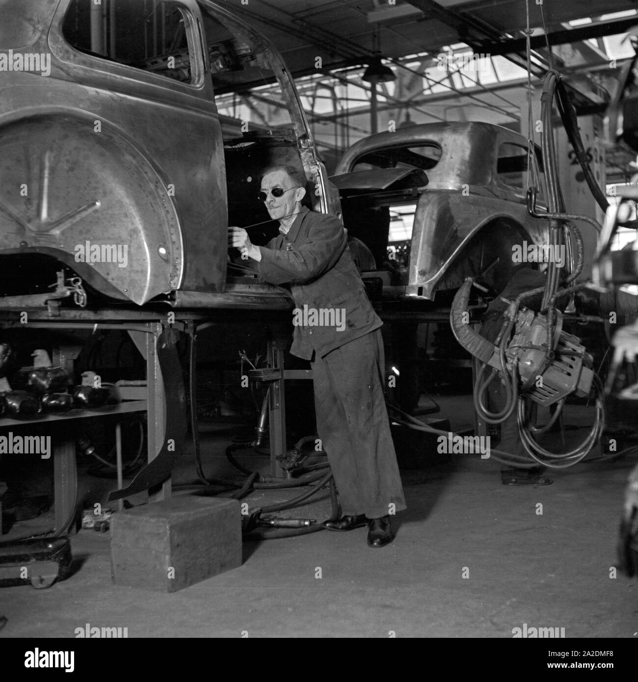Ein Arbeiter der Ford Werke in Köln Niehl am Fließband mit Karosserien, Deutschland 1930er Jahre. A worker at the conveyor belt of the Ford factory at Cologne, Germany 1930s. Stock Photo