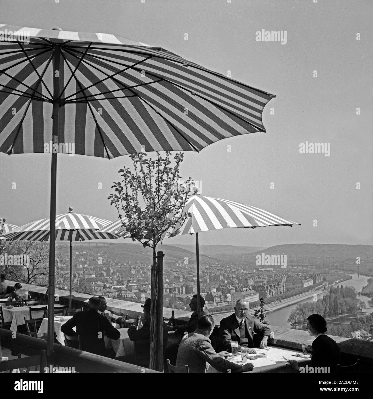 Gäste sitzen in einer Außengastronomie über den Dächern von Würzburg, Deutschland 1930er Jahre. Guests sitting on a terrace of a restaurant over the rooftops of Wuerzburg, Germany 1930s. Stock Photo