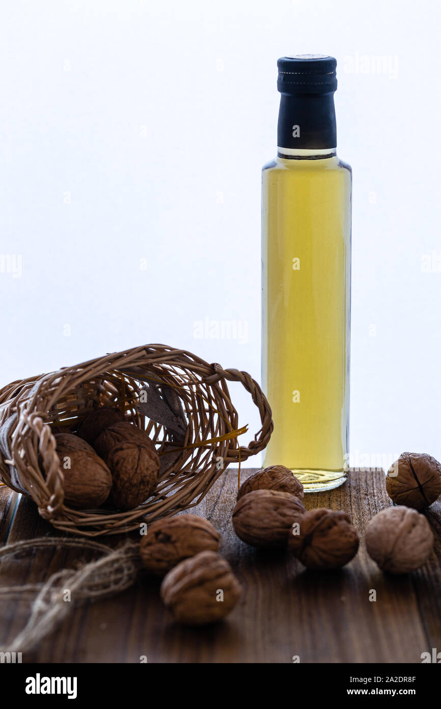 Nut oil in a glass bottle. Natural product. Walnuts for oil. Perfect for salads. Vegetarian food. Own cultivation. Photo on a white background. Stock Photo