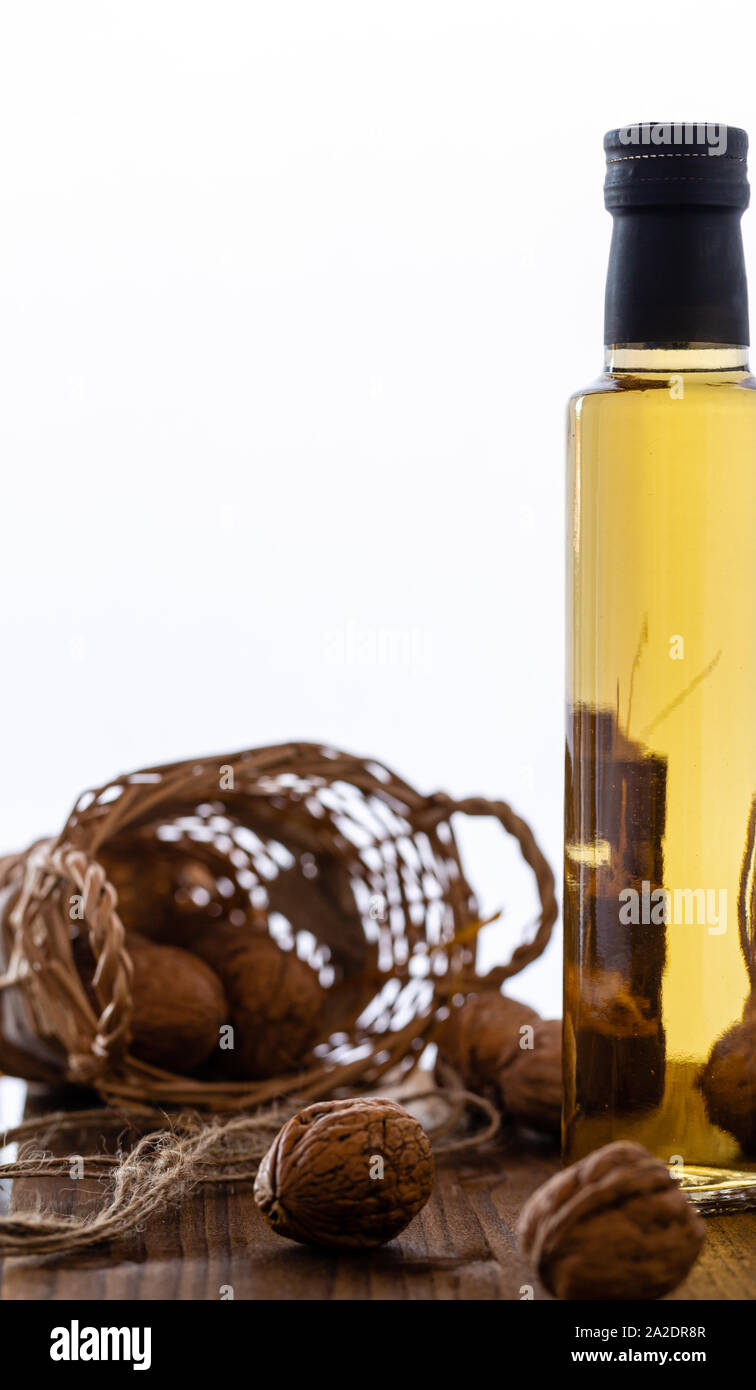Nut oil in a glass bottle. Natural product. Walnuts for oil. Perfect for salads. Vegetarian food. Own cultivation. Photo on a white background. Stock Photo