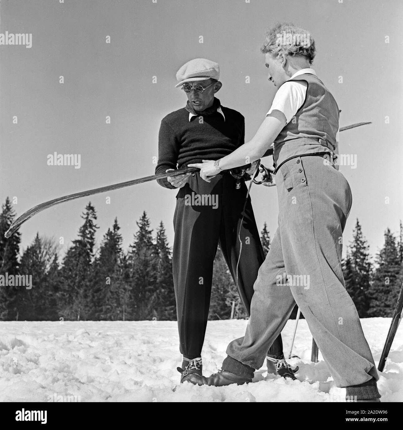 Zwei Skifahrer fachsimpeln über ihre Skier, Deutschland 1930er Jahre. Two ski tourists talking shop about their skis, Germany 1930s. Stock Photo