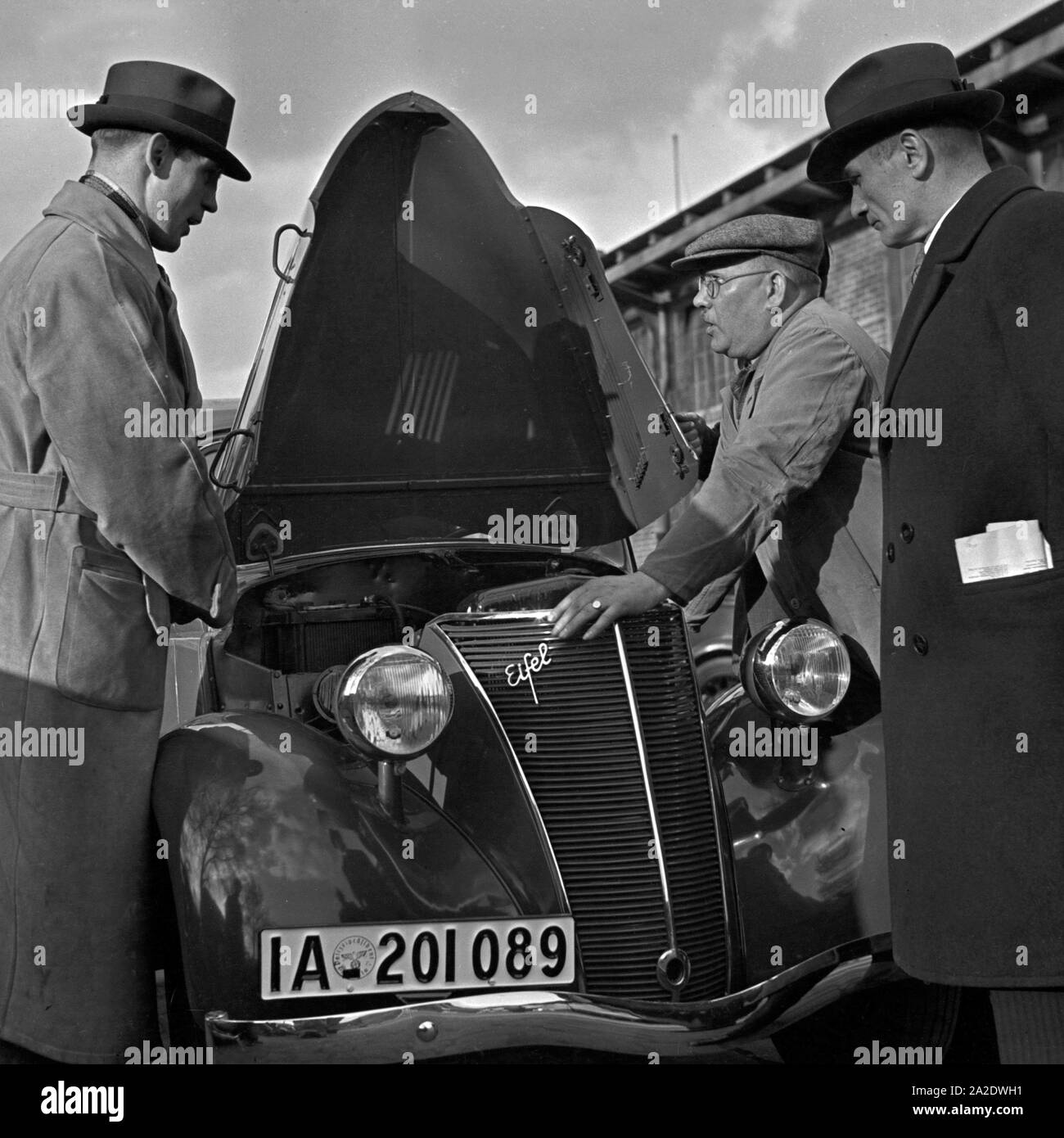 Fachgespräche mit dem Mechaniker am Motor eines Ford Eifel, Deutschland 1930er Jahre. Expert discussion with the garage manager at the bonnet of a Ford Eifel, Germany 1930s. Stock Photo