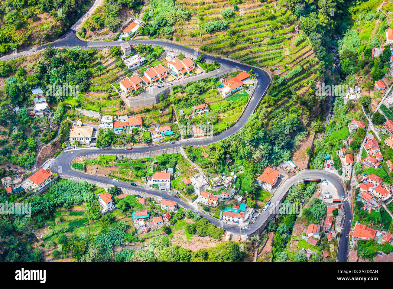 Aerial view of a village Curral das Freiras, Madeira Island, Portugal. Rural houses, green terraced fields, and scenic serpentine road photographed from above. Aerial landscape. Travel destination. Stock Photo