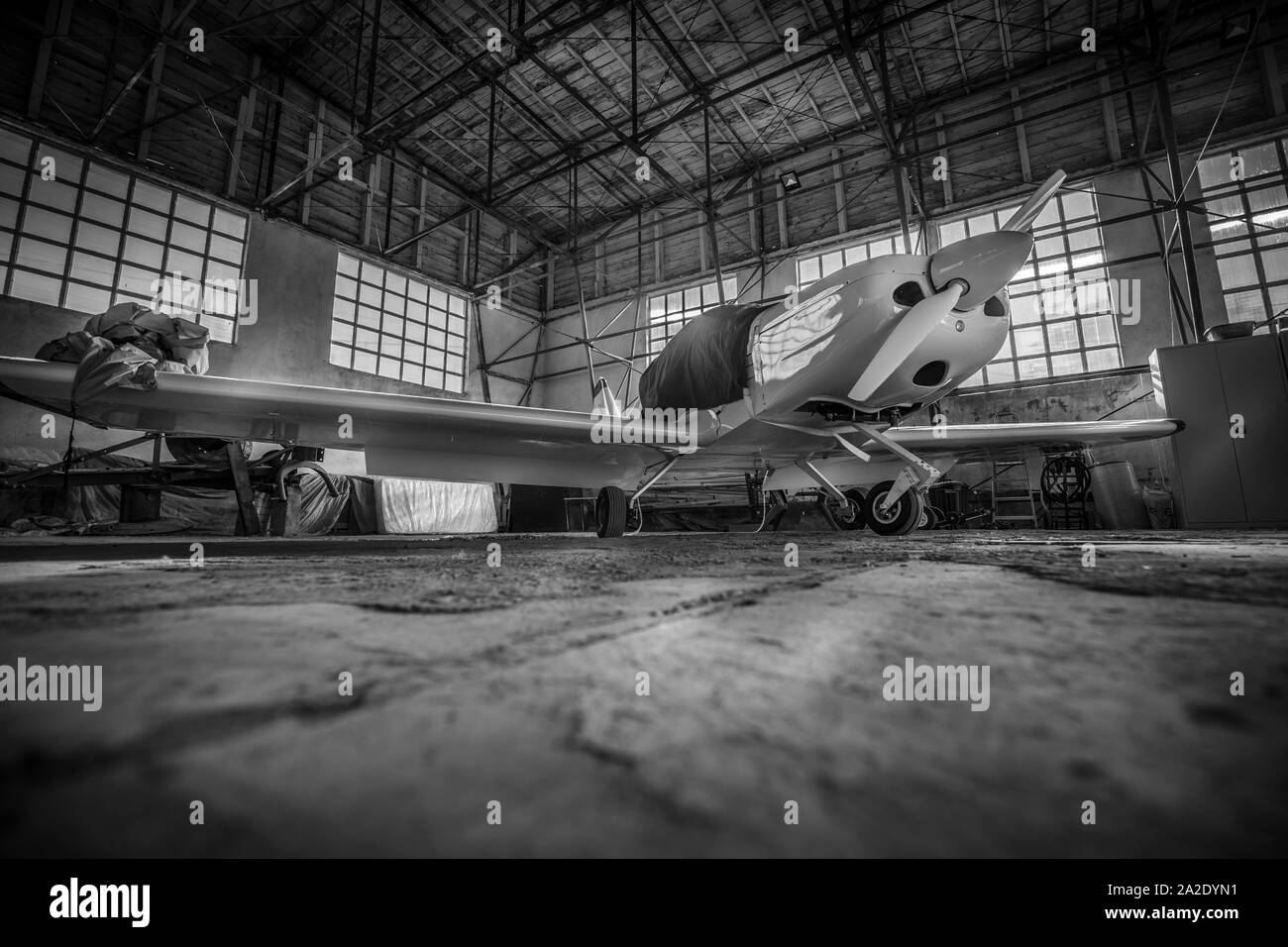 Black and white small plane inside hangar in daylight, in Romanian countryside Stock Photo