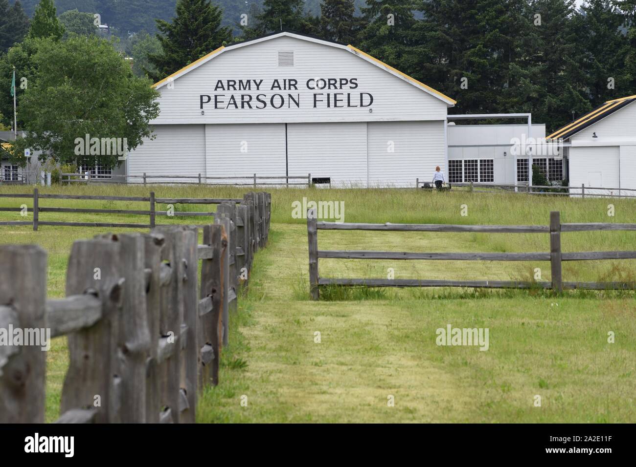 A wood fence leads to a historic hanger at Pearson Field. The main hanger is now used for Pearson Air Museum. The museum is part of Fort Vancouver. Stock Photo