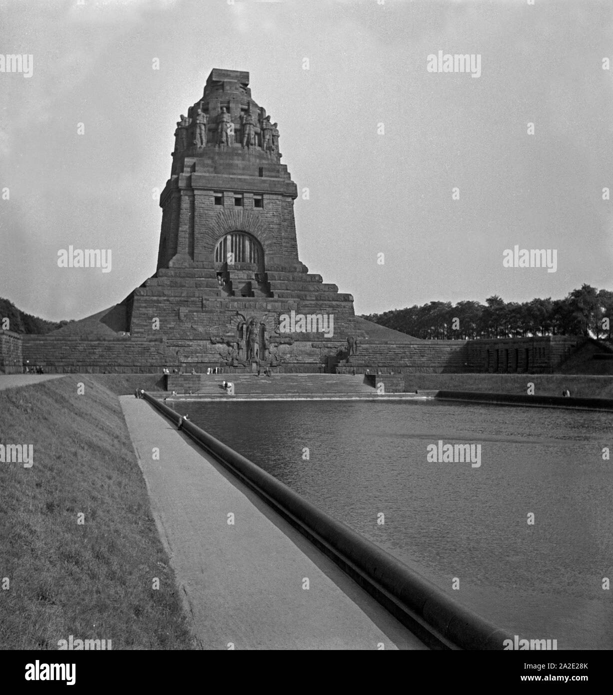 Das Völkerschlachtdenkmal und der vorgelagerte See der Tränen um die gefallenen Soldaten in Leipzig durch einen Durchgang, Deutschland 1930er Jahre. View to the monument to the battle of the nations and the lake of tears for the fallen soldiers at Leipzig, Germany 1930s. Stock Photo