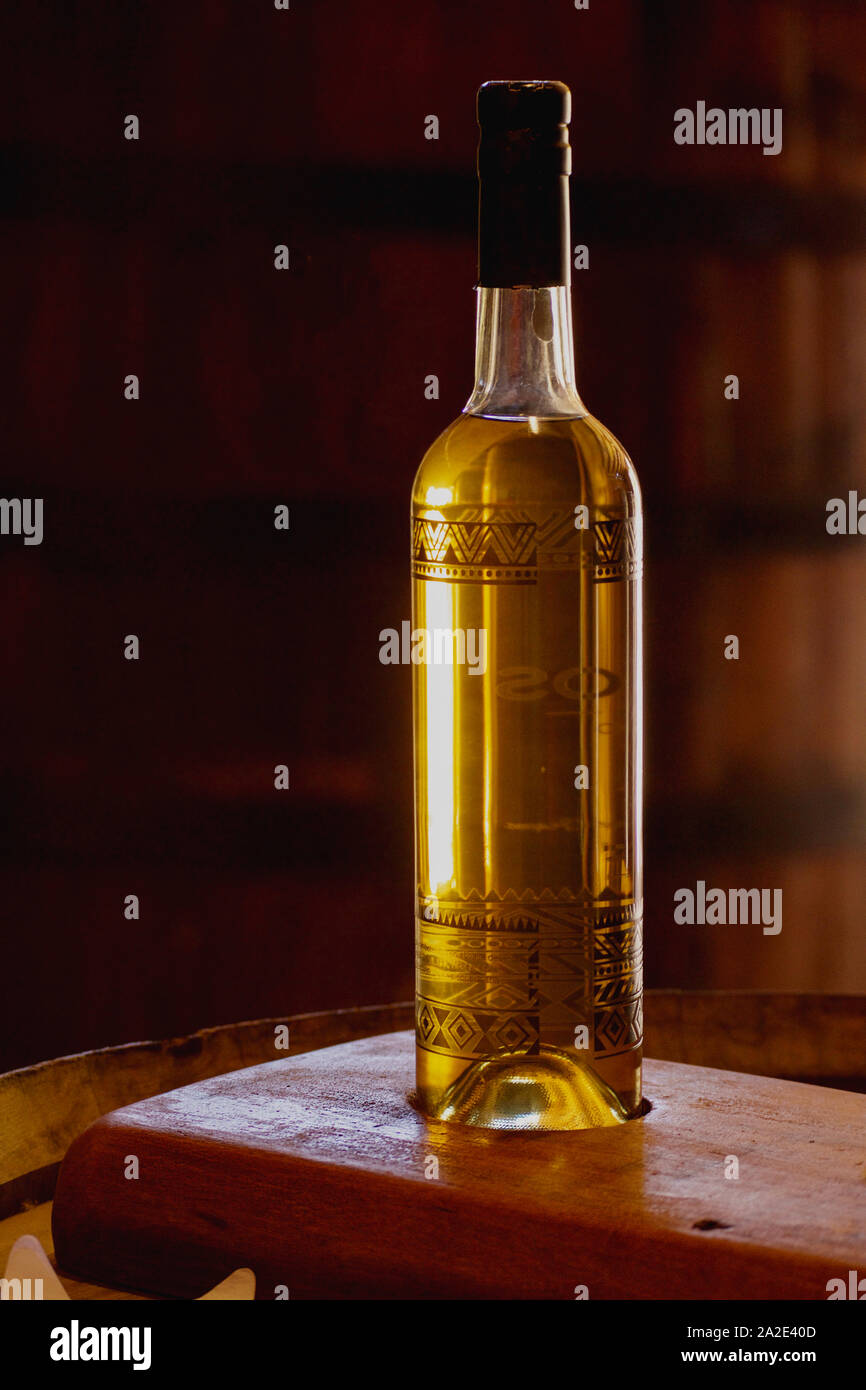 Bottle of grape liquor on a wooden barrel in a cellar. Stock Photo