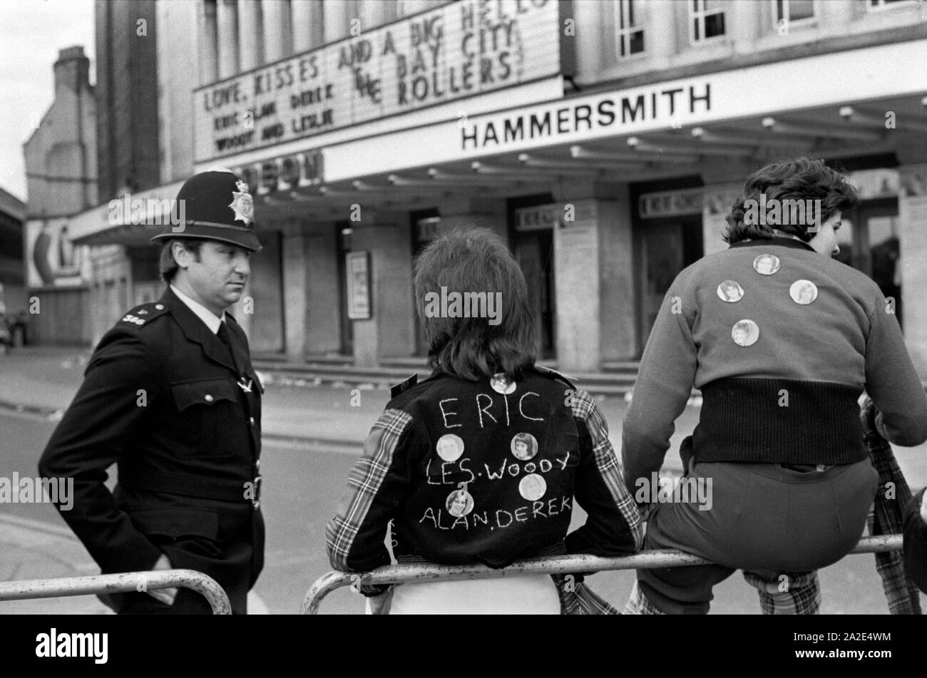 Bay City Roller Fans pop group leave pop concert at Hammersmith Odeon, west London 1975. They are wearing the Bay City Roller tartan fashion 1970s Policeman on duty chatting to teenagers. 70s England HOMER SYKES Stock Photo