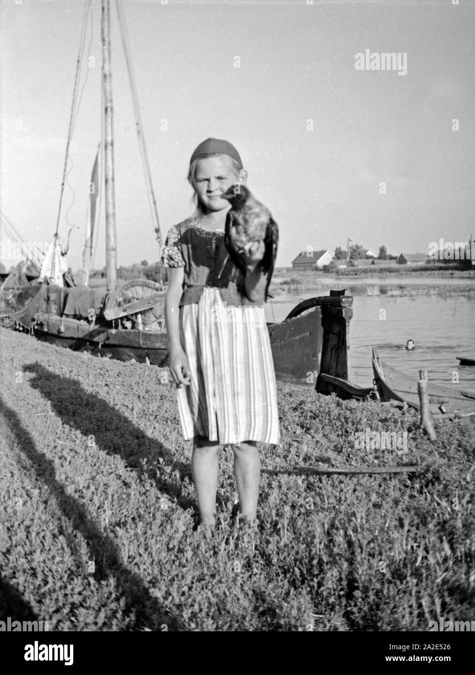 Ein kleines Mädchen hält einen Vogel in der Hand im Memeldelta, Ostpreußen, 1930er Jahre. A little girl with a bird in her hand in the Memel delta, East Prussia, 1930s. Stock Photo