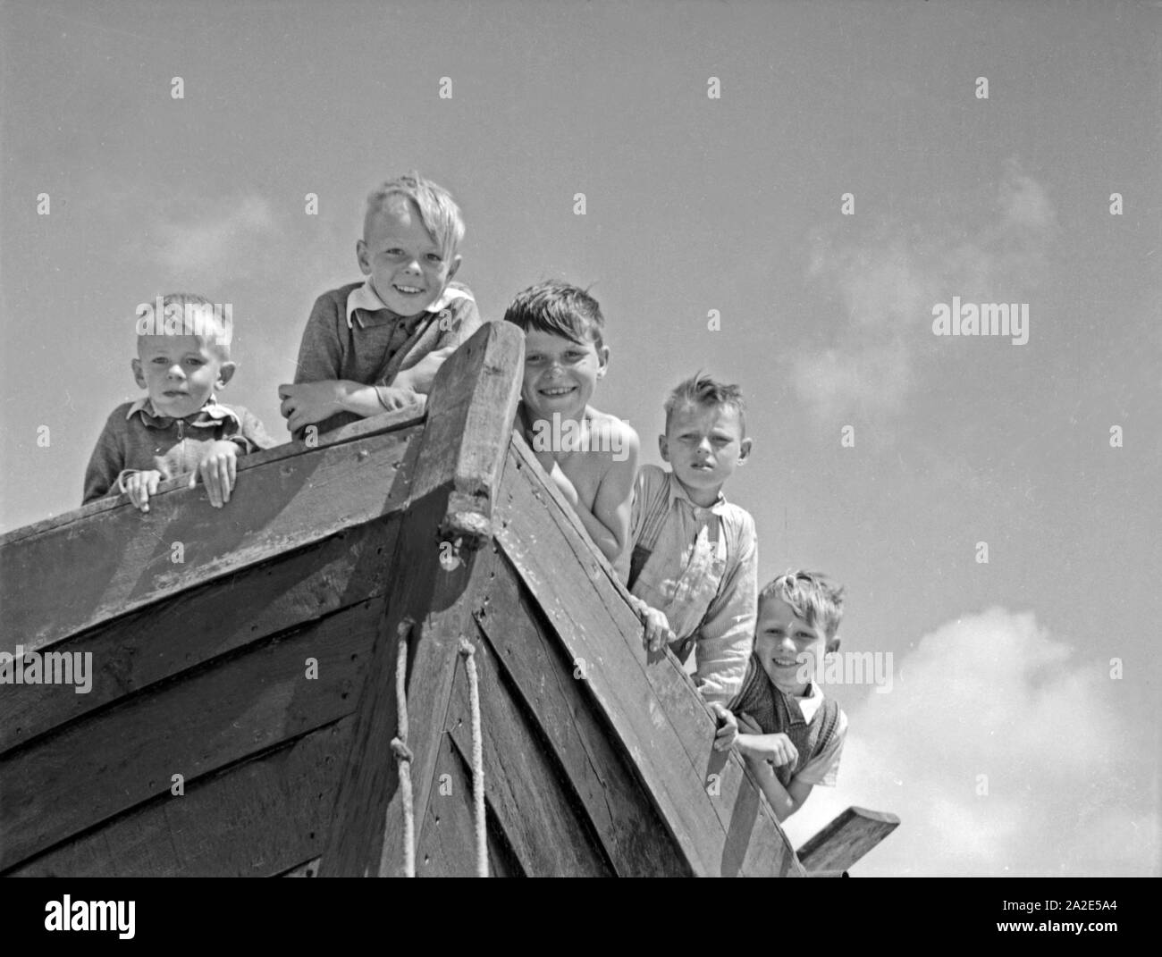 Lachende Fischerkinder am Bug eines Boots in Ostpreußen, 1930er Jahre. Happy children at the bow of a boat, East Prussia, 1930s. Stock Photo