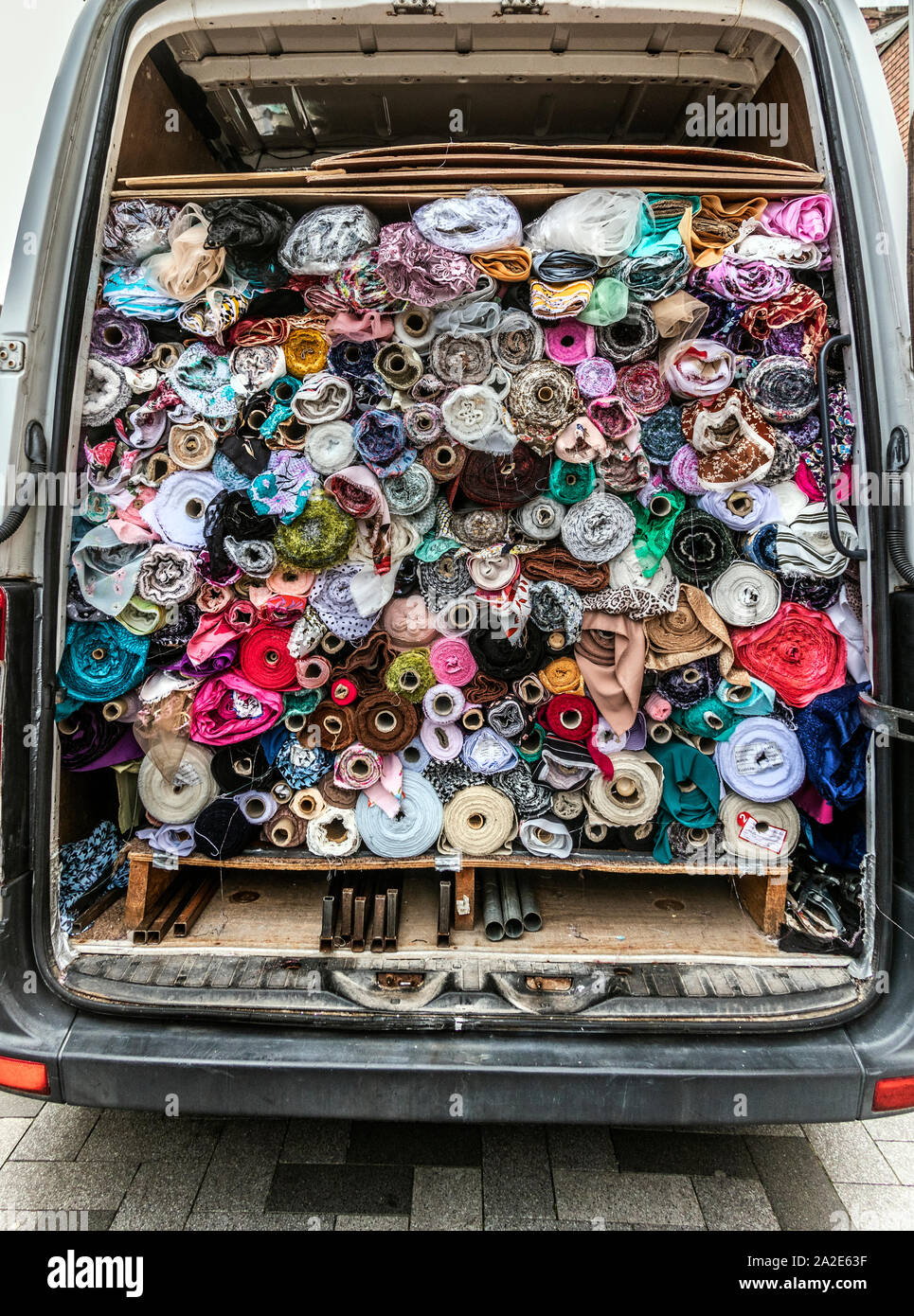 Local trader fills his van with rolls of cloth and textiles after a day selling at his outdoor market stall. The  high street, West Bromwich, West Midlands, UK. Stock Photo