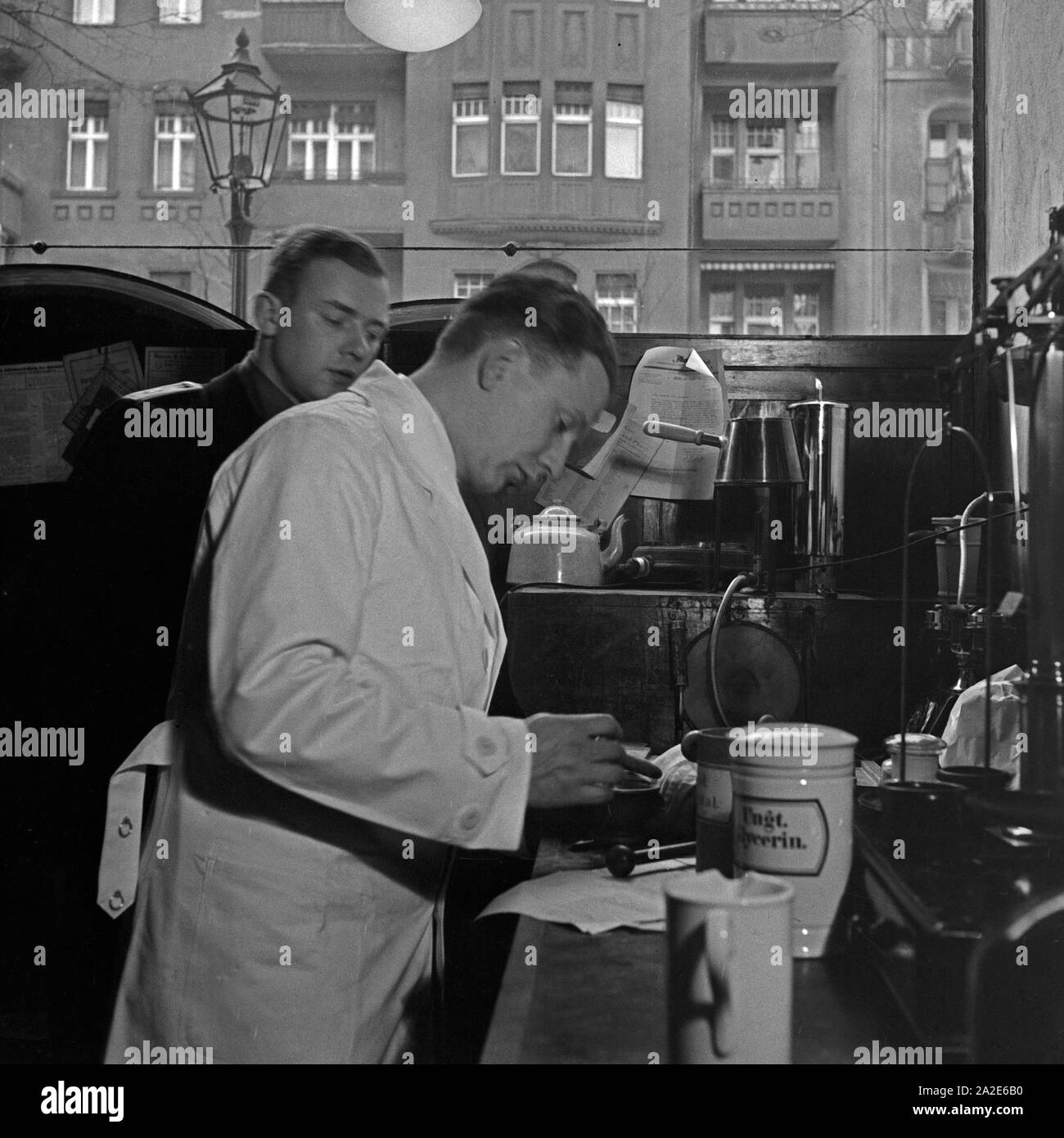 Ein Apothekerlehrling stellt unter Aufsicht ein Medikament zusammen, Deutschland 1930er Jahre. A pharmacy trainee is watched by mixing and producing medicine, Germany 1930s. Stock Photo