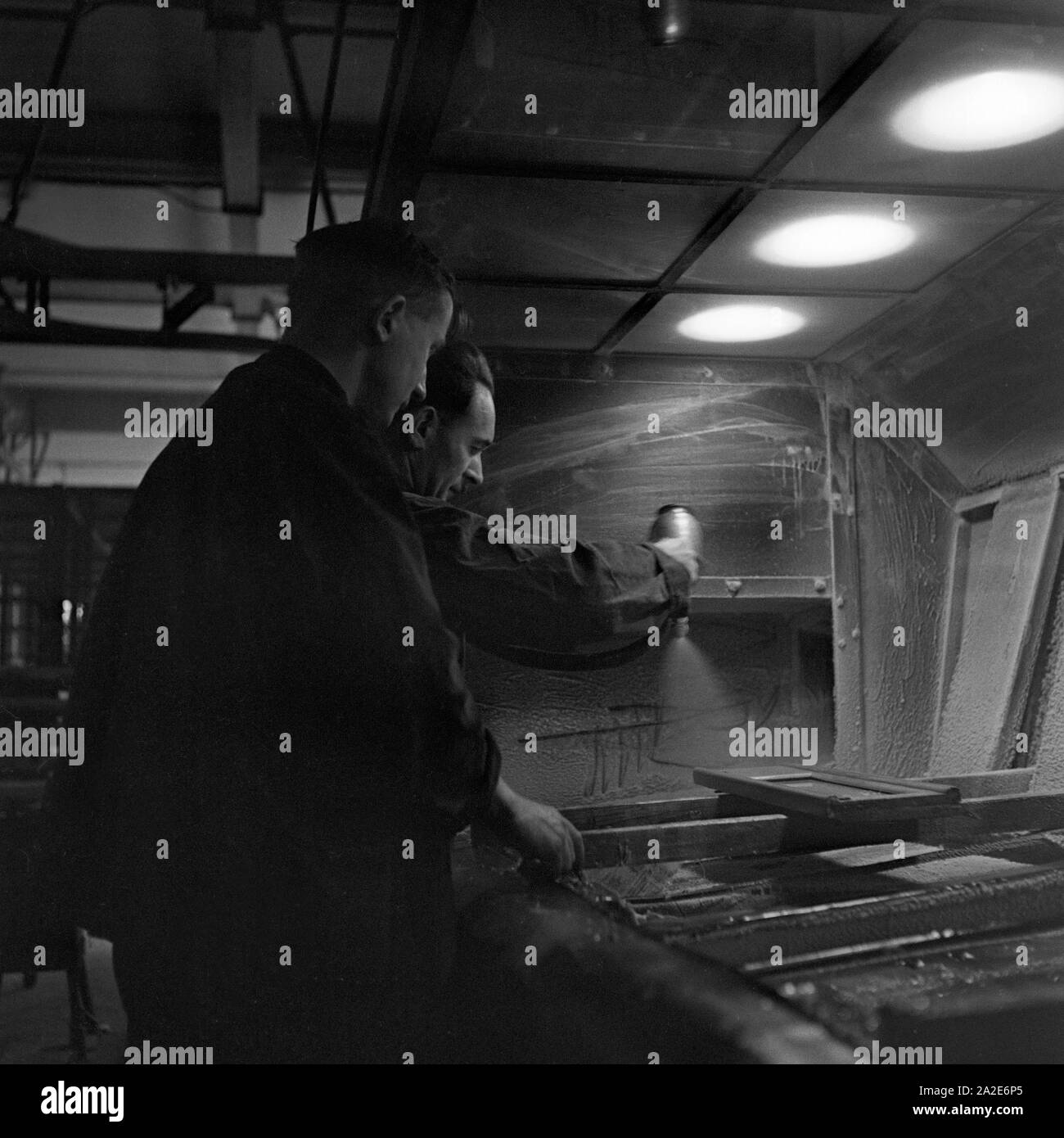 Zwei Arbeiter in einem Walzenwerk an ihrem Arbeitsplatz, Deutschland 1930er Jahre. Two workers at their working place at a roll thread factory, Germany 1930s. Stock Photo