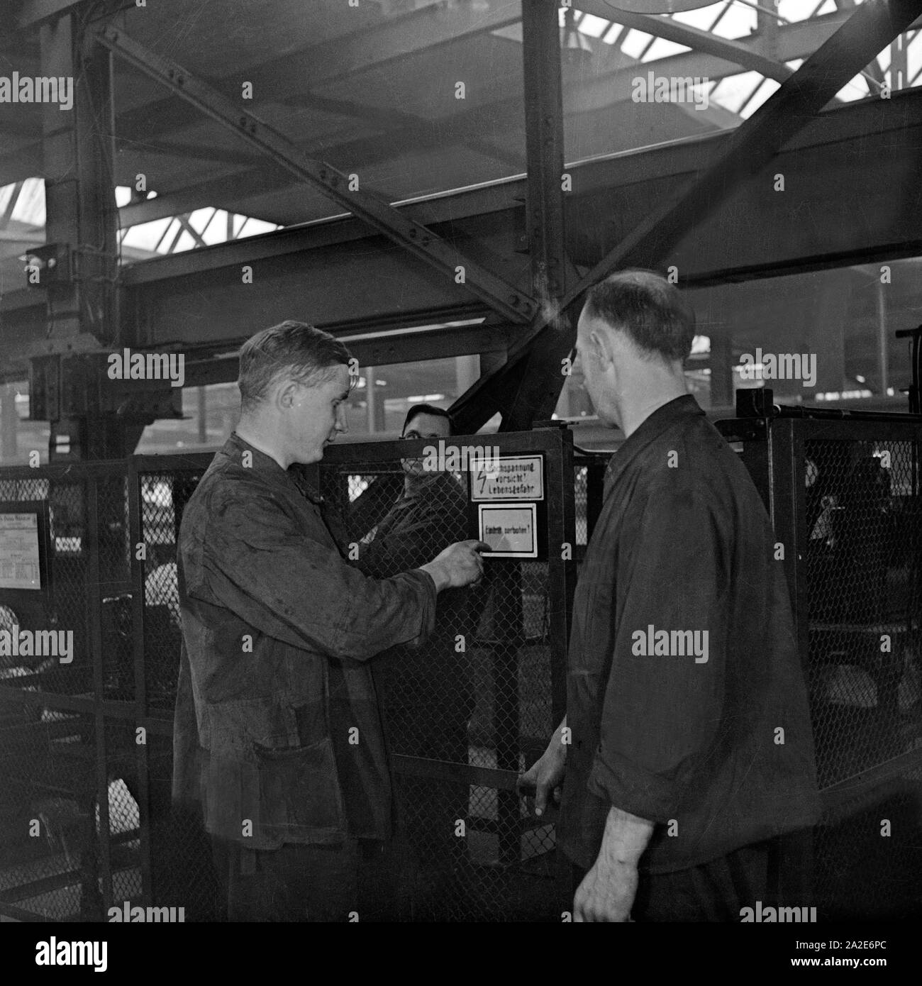 Arbeiter und Schilder zur Warnung vor Hochspannung im S-Bahn Ausbesserungswerk, Deutschland 1930er Jahre. Worker and warning signs of high voltage at a railway reparing factory, Germany 1930s. Stock Photo