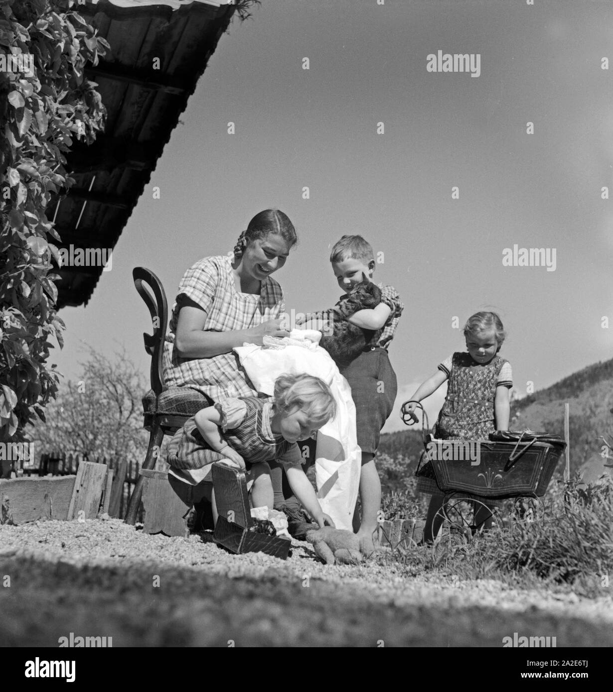 Eine junge Frau kümmert sich um Kleinkinder in Hohenaschau im Chiemgau im Rahmen des Frauenarbeitsdienstes, Deutschland 1930er Jahre. A young woman babysitting toddlers at Hohenaschau at Frauenarbeitsdienst female workforce, Germany 1930s. Stock Photo