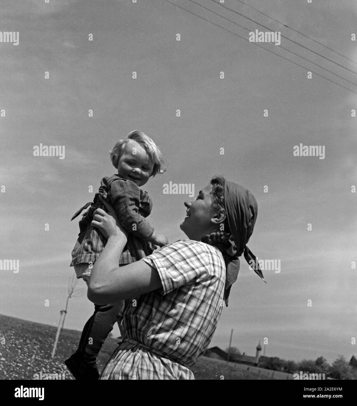 Eine junge Frau mit einem Kleinkind auf dem Arm in Hohenaschau im Chiemgau im Rahmen des Frauenarbeitsdienstes, Deutschland 1930er Jahre. A young woman holding a toddler at Hohenaschau at Frauenarbeitsdienst female workforce, Germany 1930s. Stock Photo