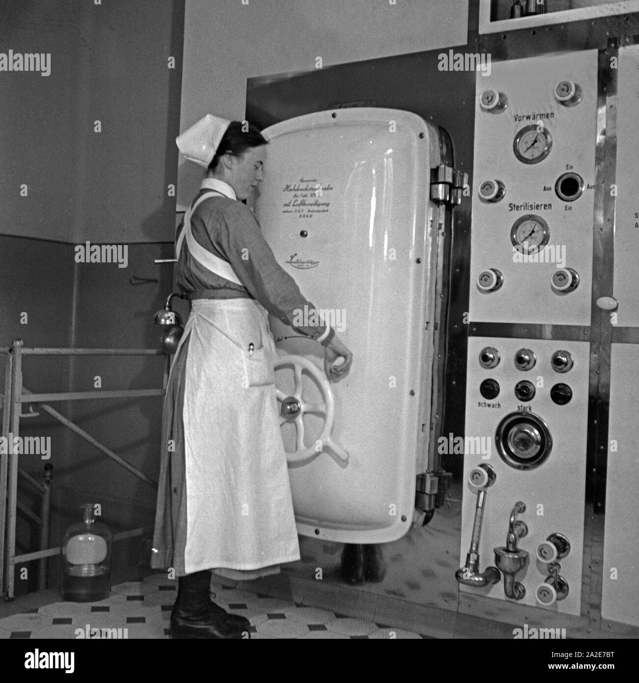 Eine Krankenschwester an einem Hochdrucksterilisator im Mütterheim Dresden auf Schloß Dittersbach, Deutschland 1930er Jahre. A nurse at a high pressure sterilizing oven at the rest centre for mothers at Dittersbach castle near Dresden, Germany 1930s. Stock Photo