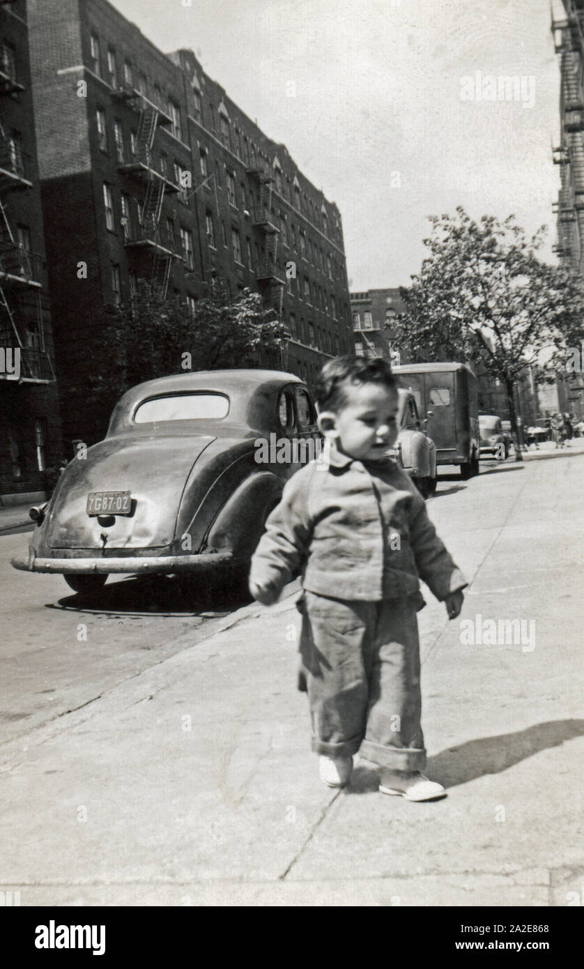 Toddler boy walking along the sidewalk in an urban city, New York, USA, circa 1949. Stock Photo