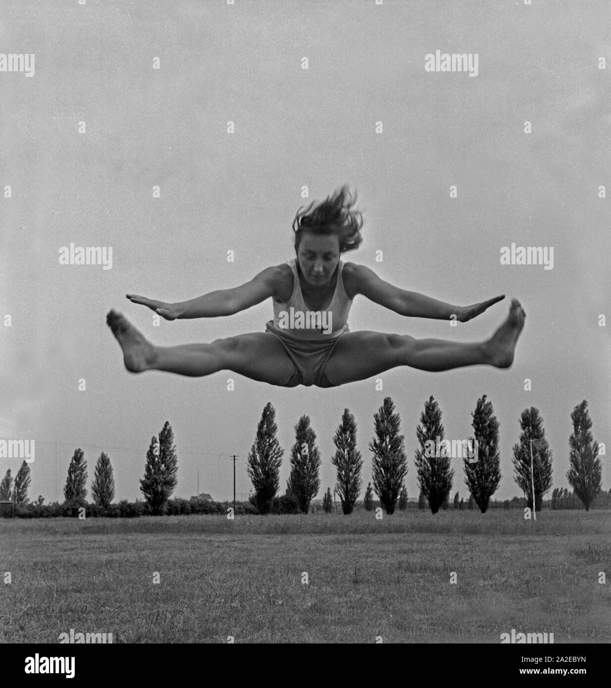 Eine Frau bei einem Sprung in der Logau Musterschule für Frauenturnen in Hannover, Deutschland 1930er Jahre. A woman doing a jump at the Logau school for women's gymnastics in Hanover, Germany 1930s. Stock Photo