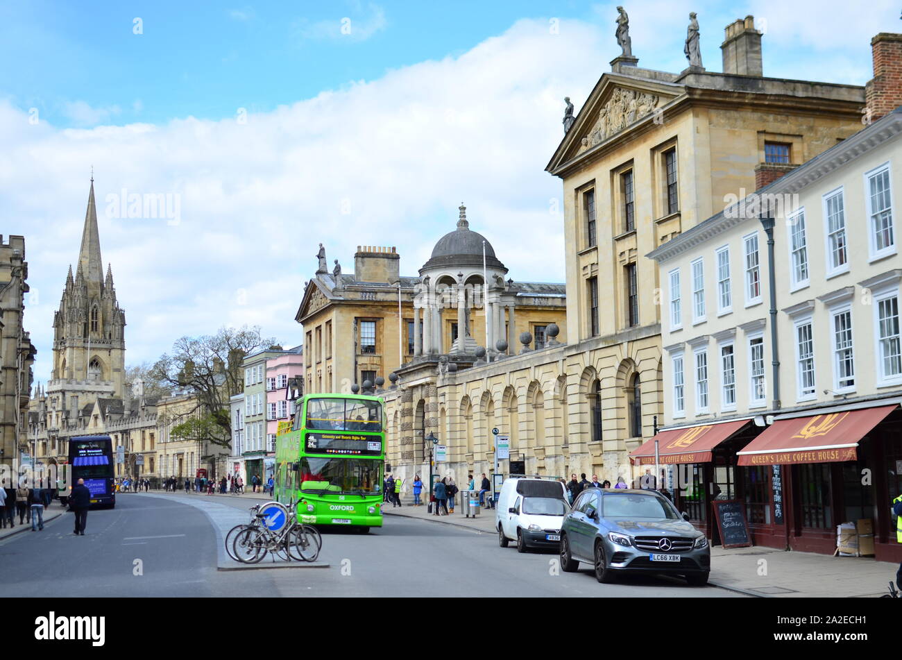 The High street in Oxford with moving green double decker bus and parked bicycle. View on The Queen's College and Church of St. Mary the Virgin Stock Photo