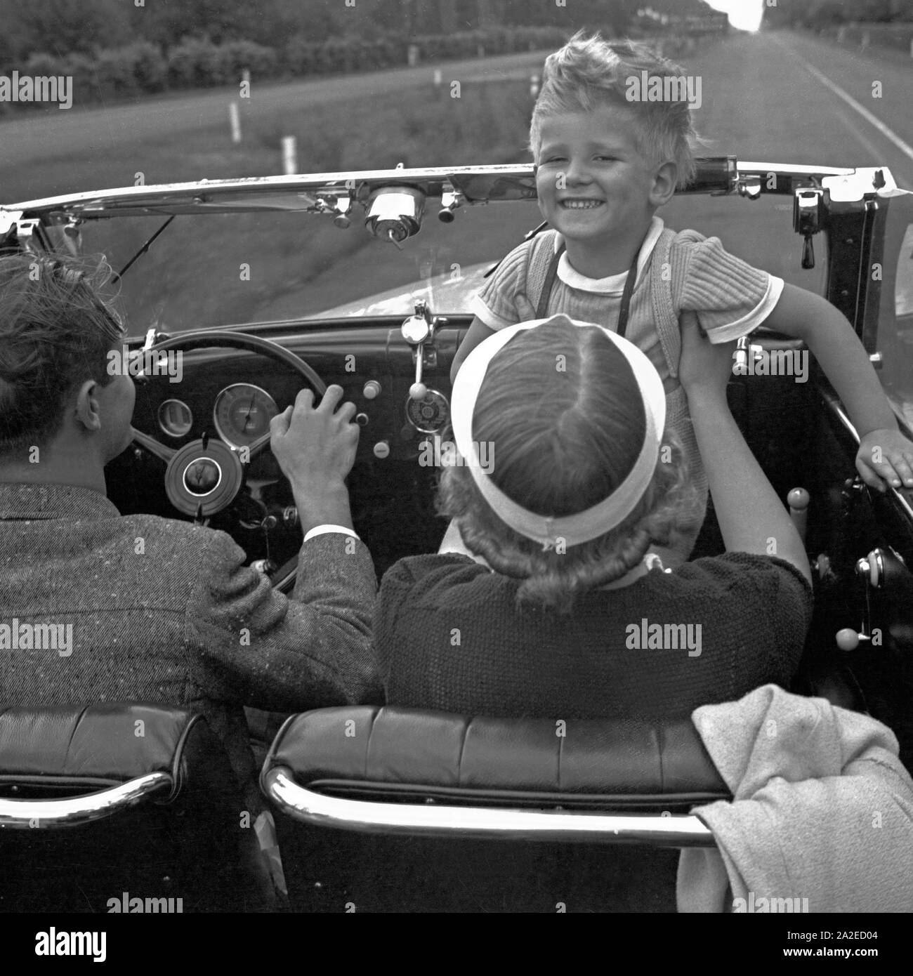Ein kleiner Junge während der Fahrt in einem Ford V8 Cabrio, Deutschland 1930er Jahre. A little boy while riding with a Ford V8 convertible, Germany 1930s. Stock Photo
