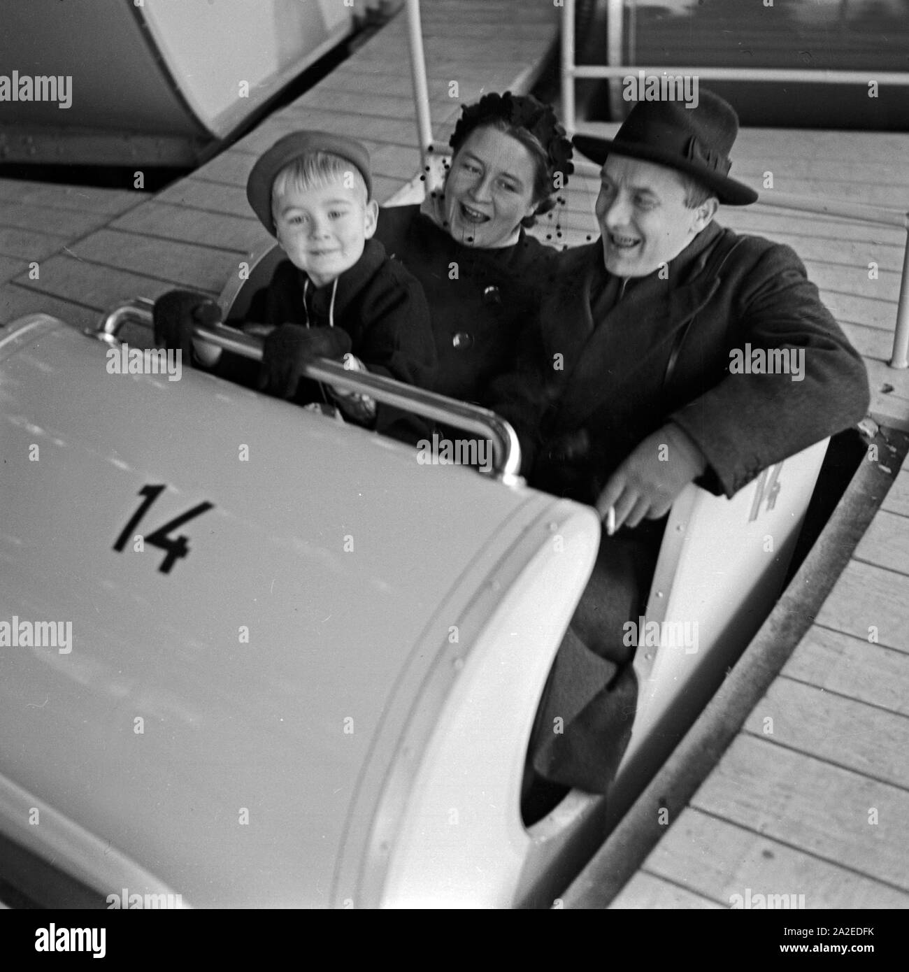 Ein kleiner Junge mit seinen Eltern in der Gondel eines Fahrgeschäfts auf dem Weihnachtsmarkt, Deutschland 1930er Jahre. A little boy with his parents in a gondola of a fairground ride at the christmas market, Germany 1930s. Stock Photo