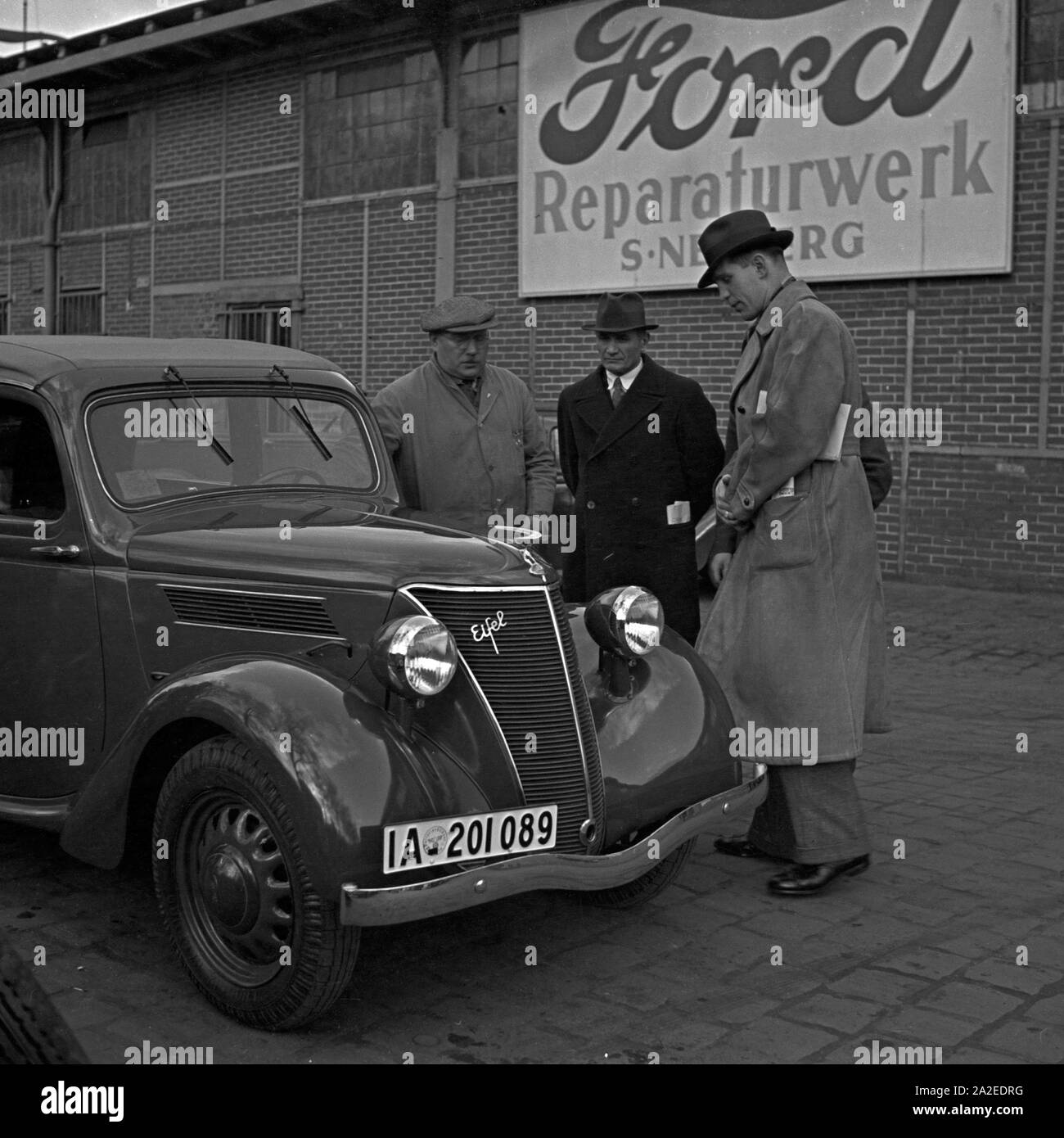 Fachgespräche mit dem Mechaniker am Motor eines Ford Eifel, Deutschland 1930er Jahre. Expert discussion with the garage manager at the bonnet of a Ford Eifel, Germany 1930s. Stock Photo