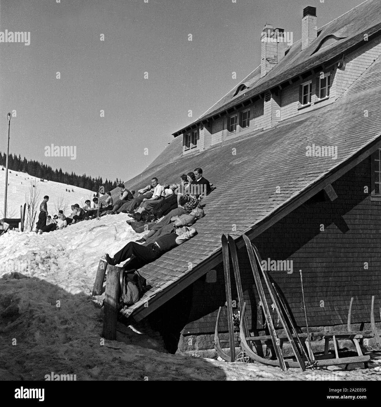 Winterurlauber beim Sonnenbad auf dem Dach einer Skihütte, Deutschland 1930er Jahre. Ski tourists sunbathing at the roof of a ski hut, Germany 1930s. Stock Photo