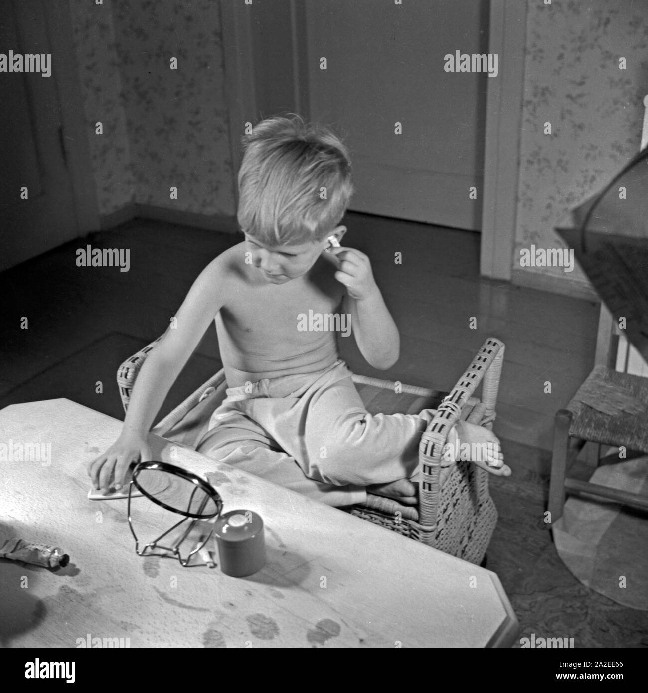 Ein kleiner Junge putzt sich seine Ohren, Deutschland 1930er Jahre. A little boy cleaning his ears, Germany 1930s. Stock Photo