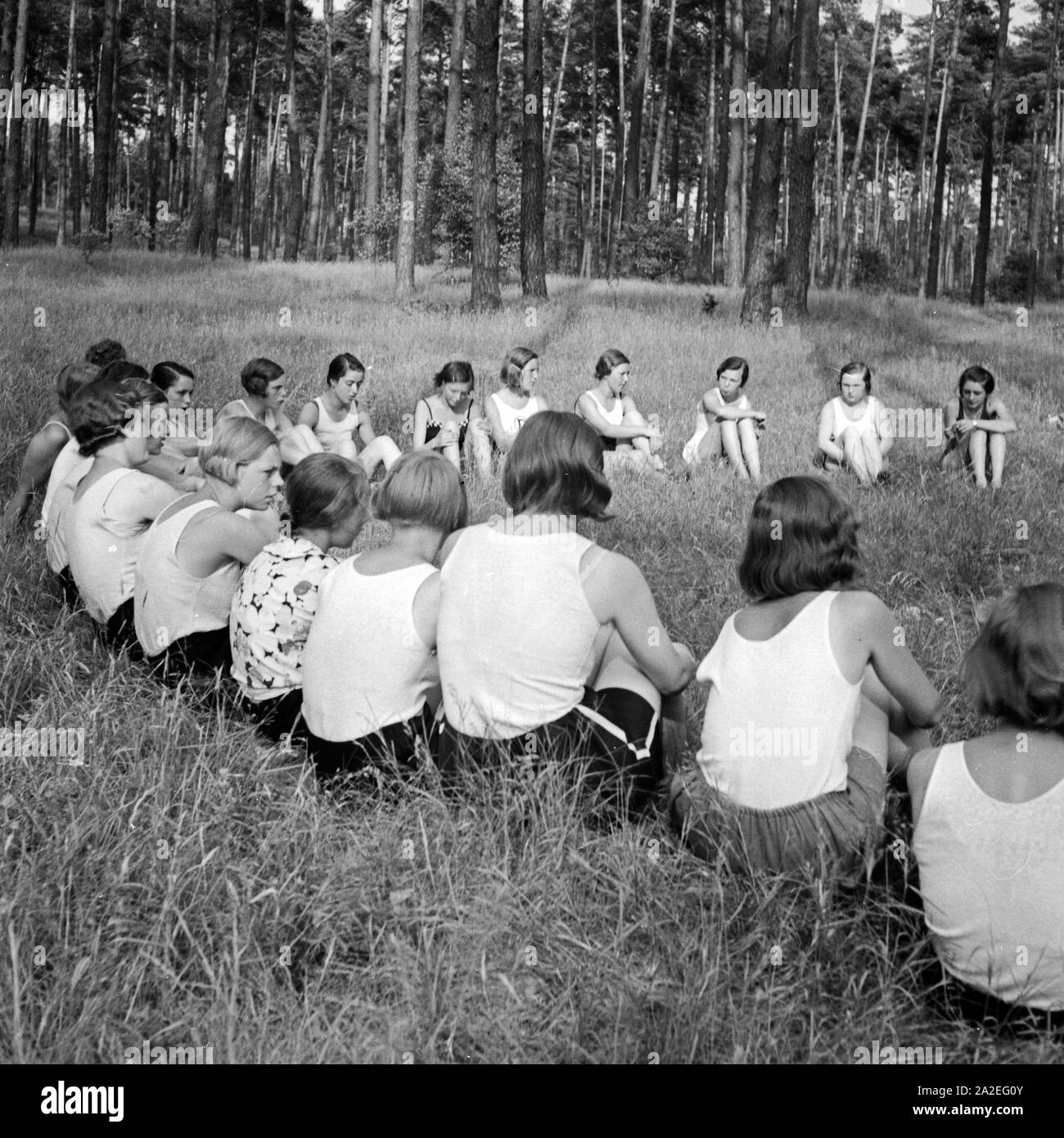 Mädchen sitzen im Wald im Kreisim Freizeitlager der Deutschen Arbeitsfront in Altenhof am Werbellinsee in Brandenburg, 1930er Jahre. Girls are sitting in a circle in the forest at Altenhof, Brandenburg, 1930s. Stock Photo