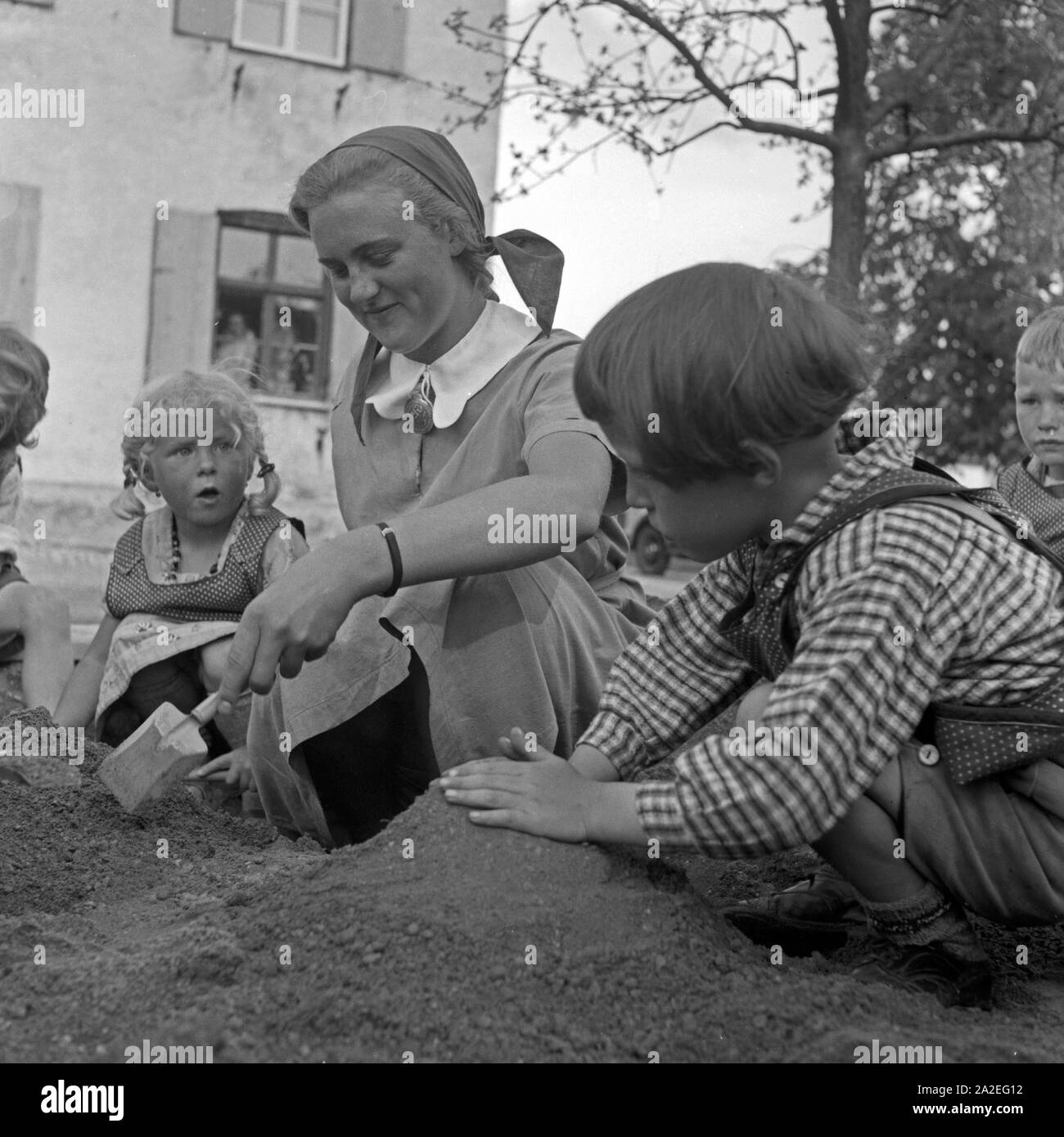 Eine Frau spielt mit kleinen Kindern beim Frauenarbeitsdienst in Kempten, Deutschland 1930er Jahre. A woman playing with toddlers at the female workforce at Kempten, Germany 1930s. Stock Photo