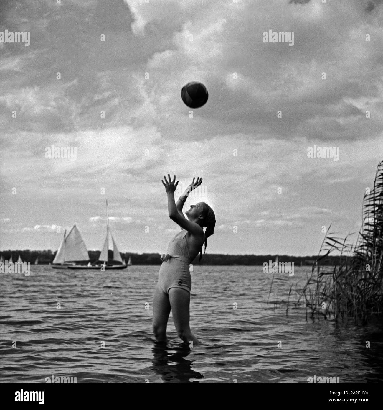 Werbefoto: eine Junge Frau spielt mit einem Wasserball am Strand eines Sees, Deutschland 1930er Jahre. Advertising: a young woman playing waterball on a beach, Germany 1930s. Stock Photo