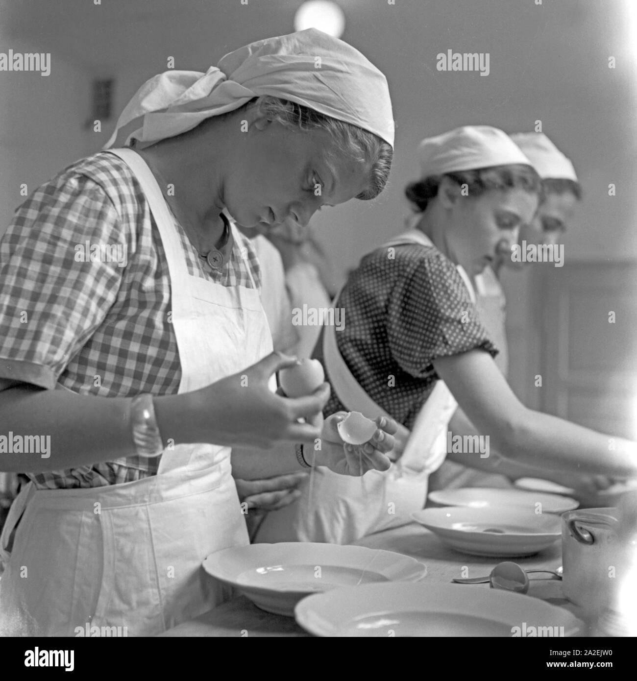 BdM girls separate egg yolks from egg white while cooking at the home school Greifenberg, Germany 1930s. BdM girls separating yolk from egg white at the domestic science school at Greifenberg, Germany 1930s. Stock Photo