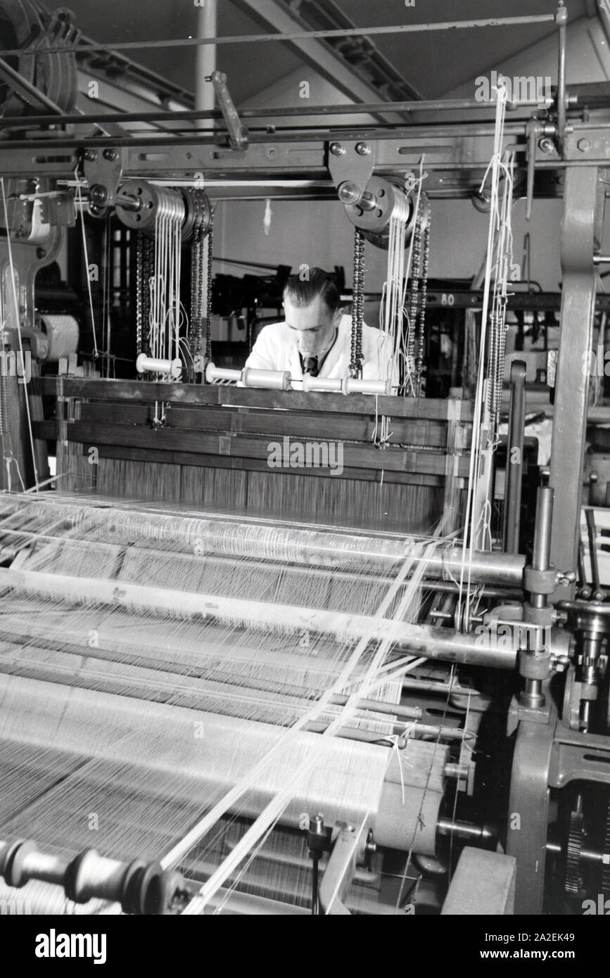 An employee in a textile company in Krefeld adjusting the yarn in the big power loom, Germany 1930s Stock Photo