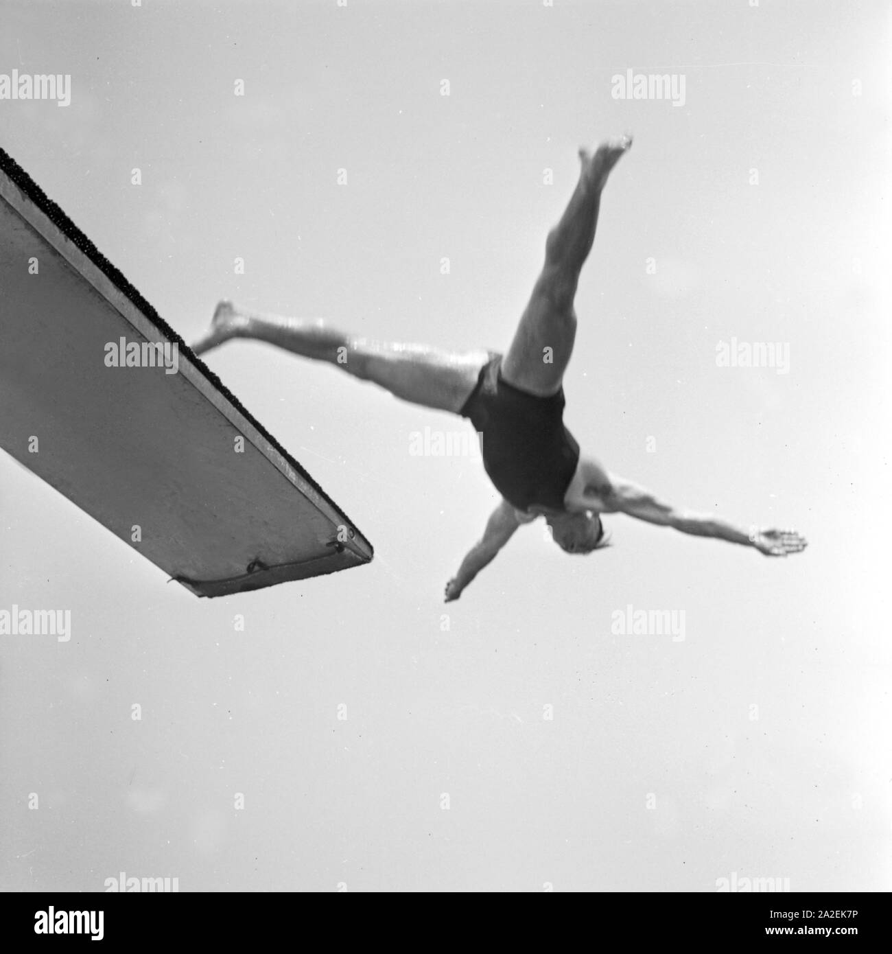 Ein Mann bei einem Sprung vom Sprungbrett ins Wasser, Deutschland 1930er Jahre. A high diver performing, Germany 1930s. Stock Photo